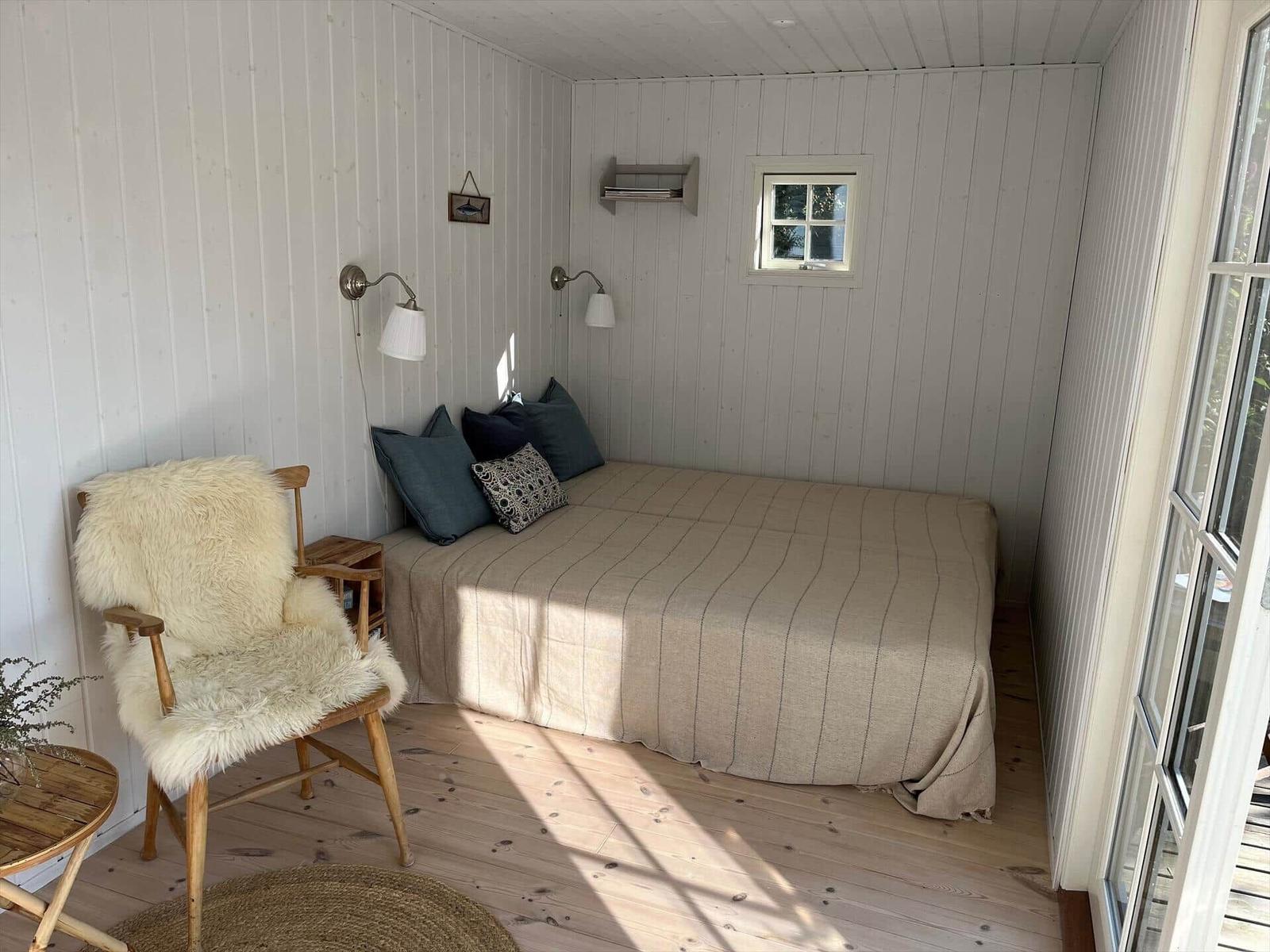 Schlafzimmer mit Bett, Kleiderschrank und Wandlampe.
