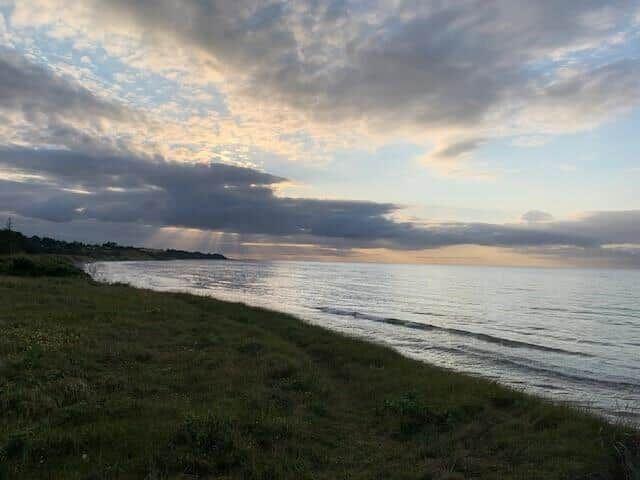 Ein weißes Boot fährt über das blaue Meer unter klarem Himmel.