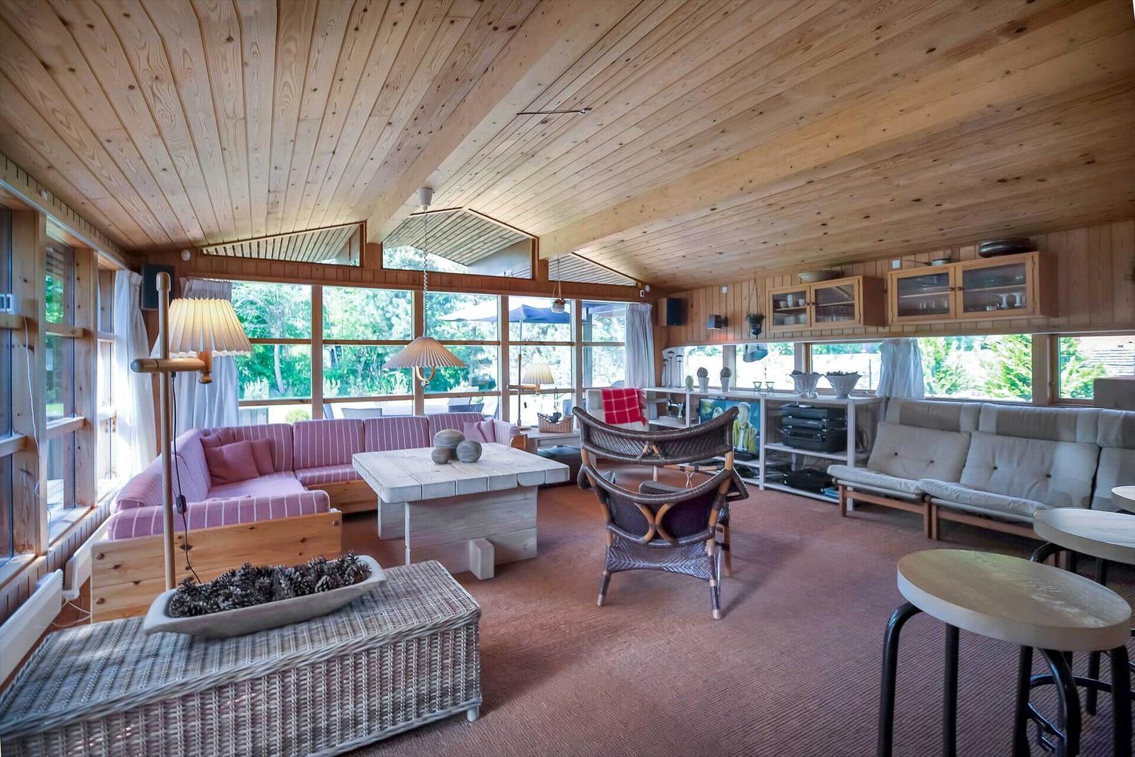 Holzterrasse mit Tisch, Stühlen und Sonnenschirm vor einem Haus mit Garten.