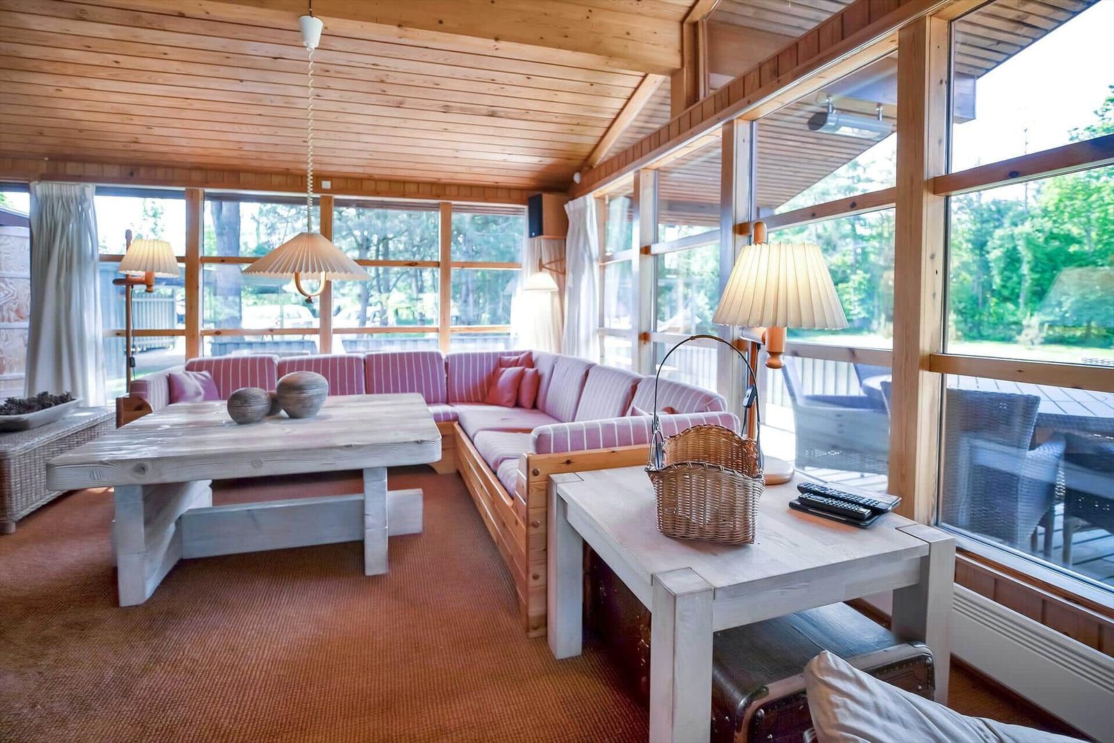 Holzterrasse mit Tisch, Liegestuhl und Blick auf Wald.