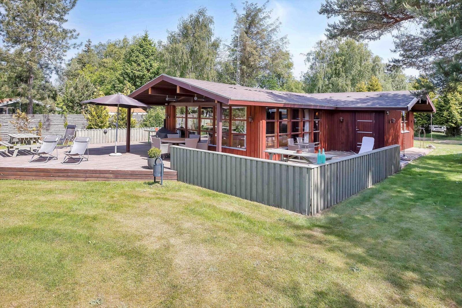 Zwei Liegestühle auf einer Holterrasse mit Blick auf einen grünen Garten und einen Hängemattenbereich.