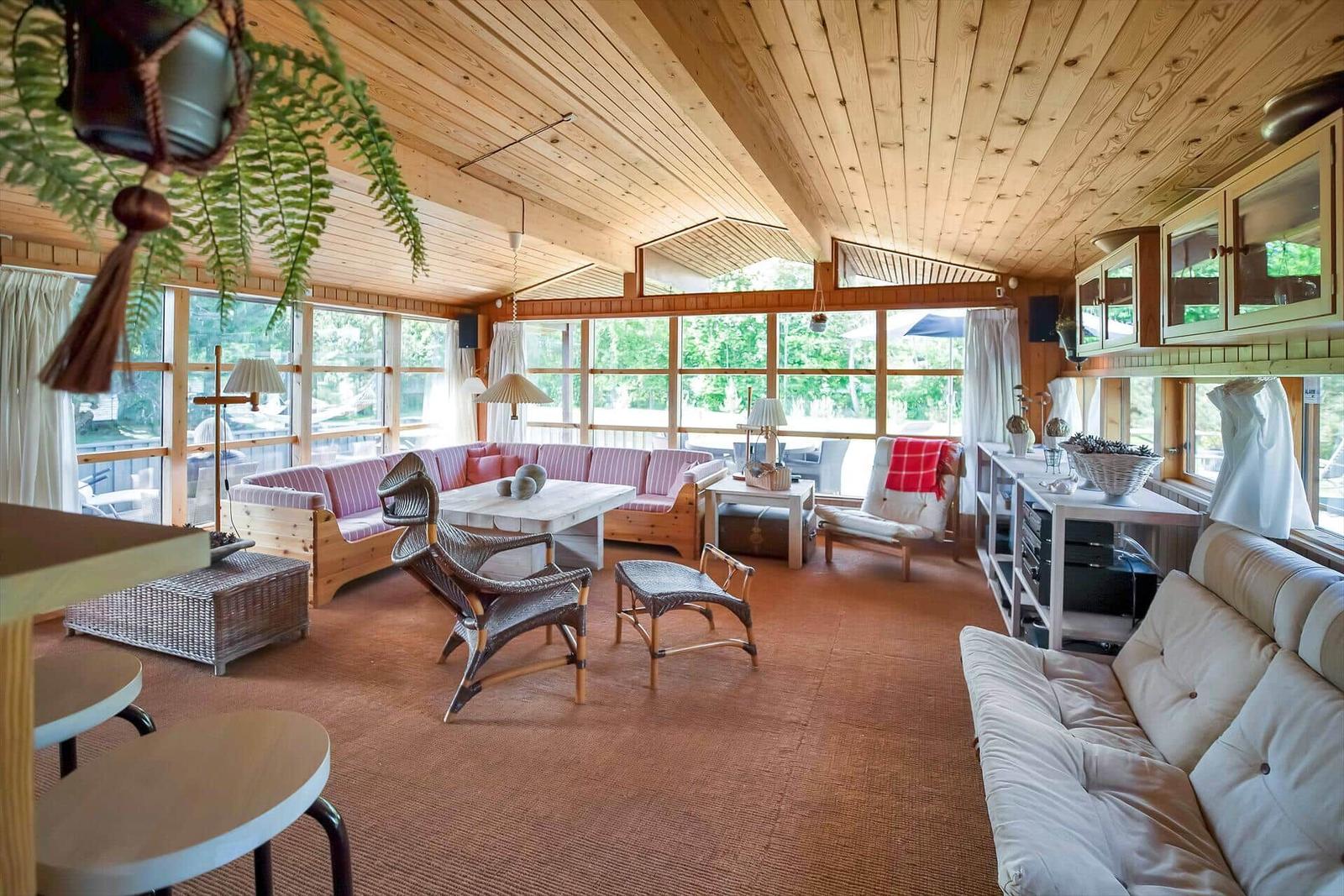 Holzterrasse mit Sitzgelegenheiten und Grillbereich vor einem Holzhaus.