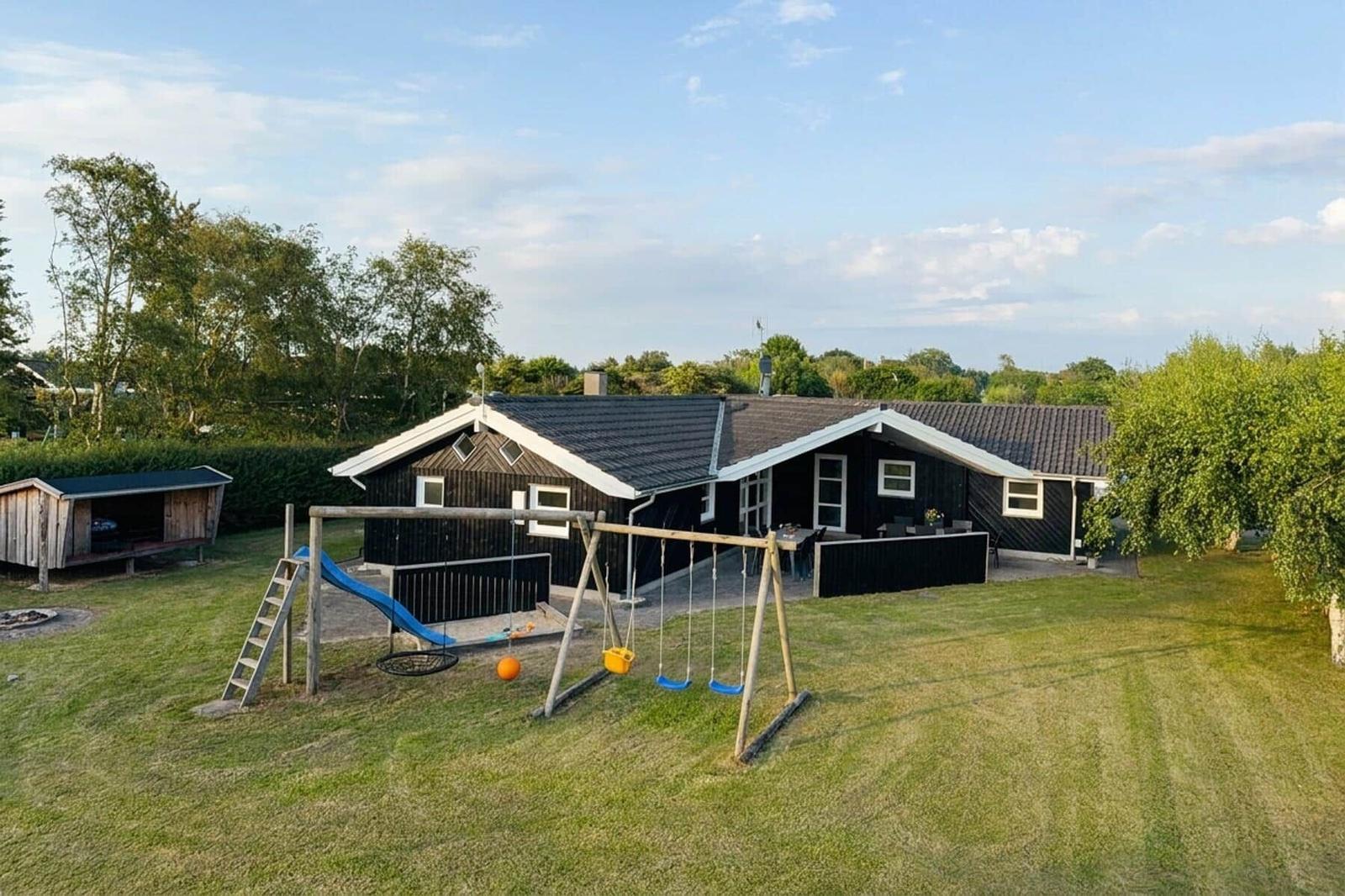 Rotes Gebäude mit Eiscreme-Schildern am Strand. Außentische und Sonnenschirme.
