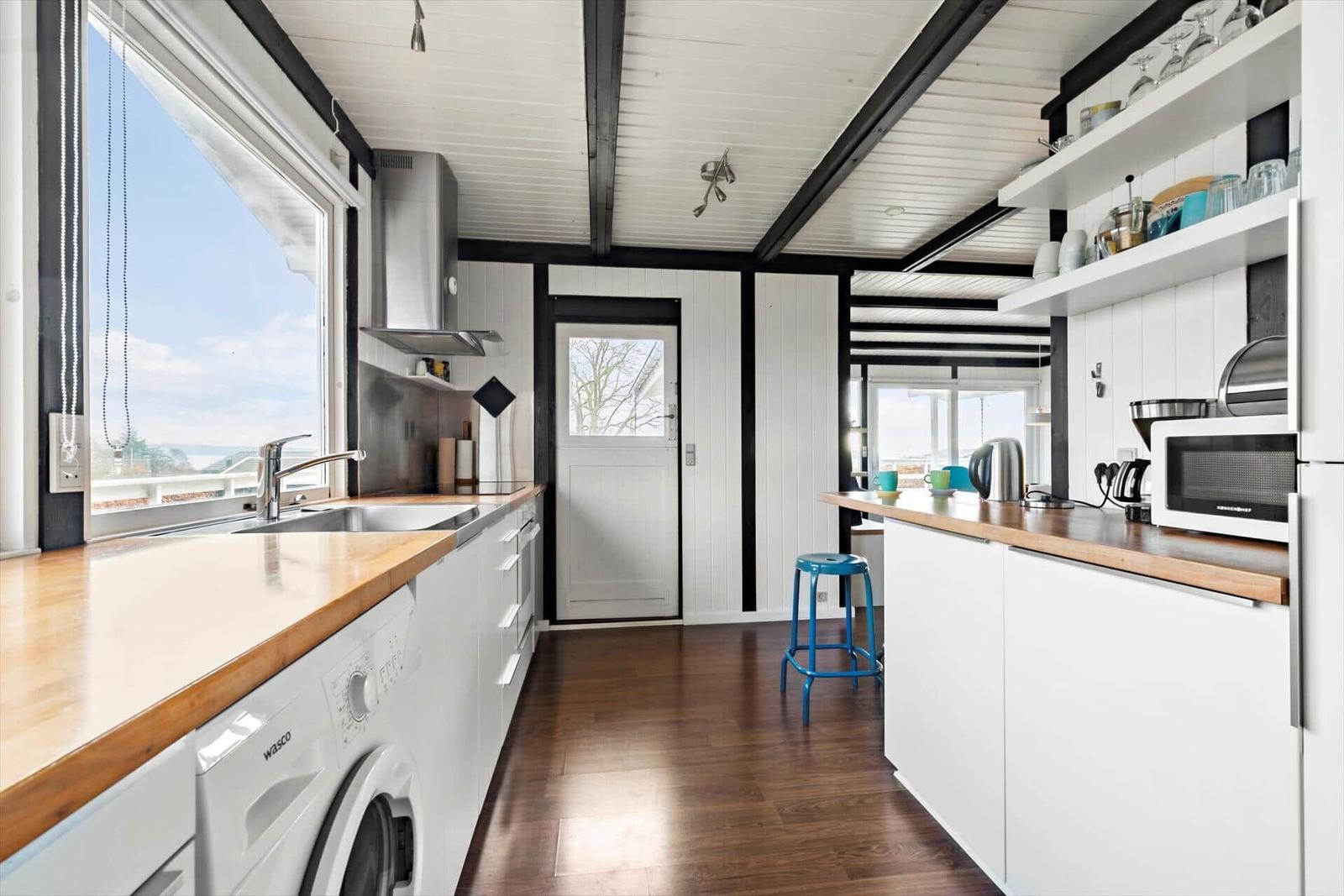 Haus mit großem Holzdeck und Sitzgelegenheiten unter Dach.