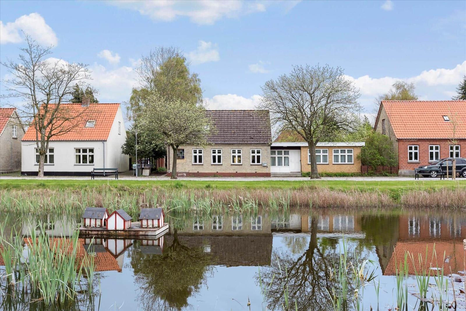 Ein gelbes Haus mit Dachfenster und mehreren Fenstern an einer Straße.