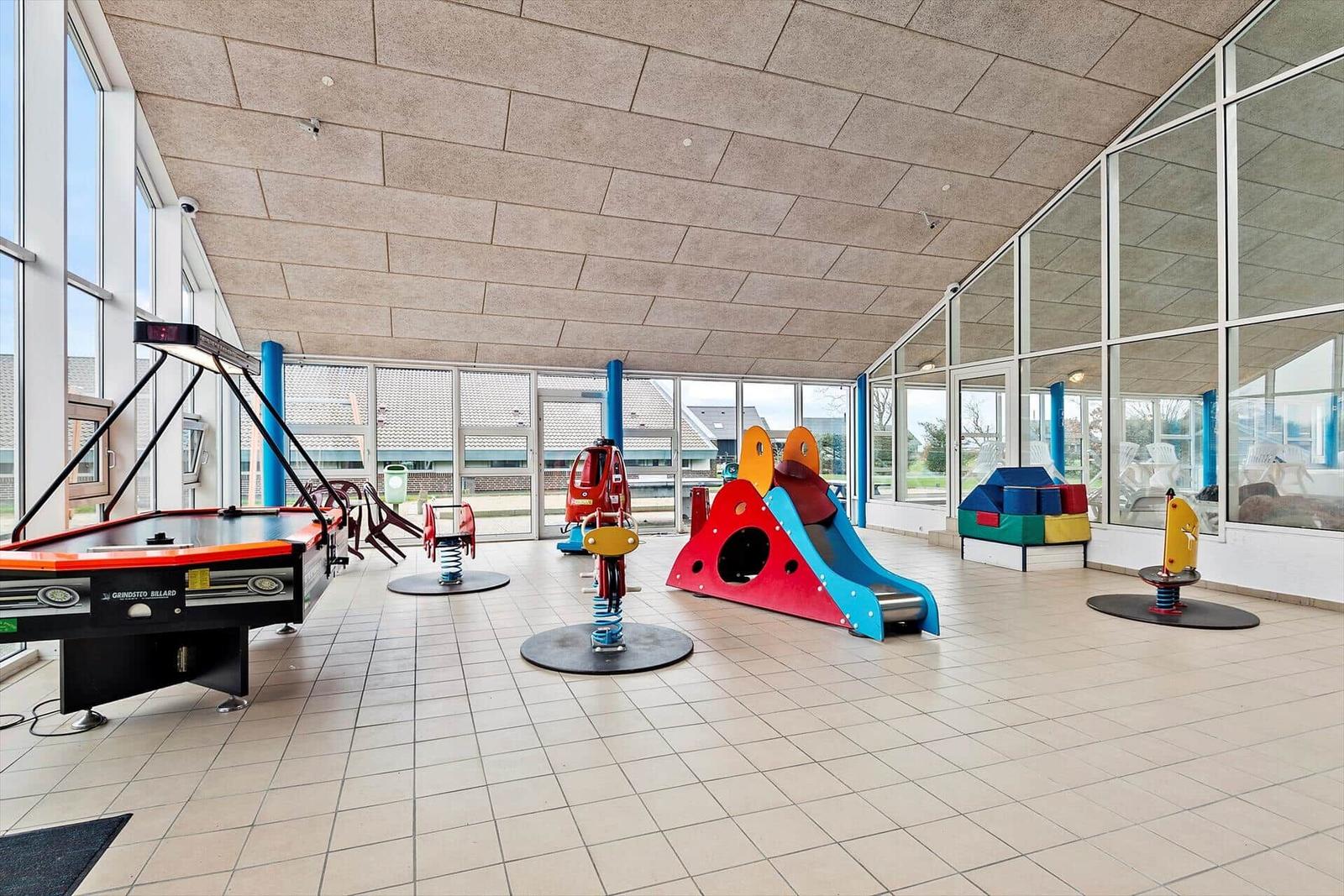 Spielplatz mit Klettergerüst und Schaukel auf Sandfläche vor einem Gebäude