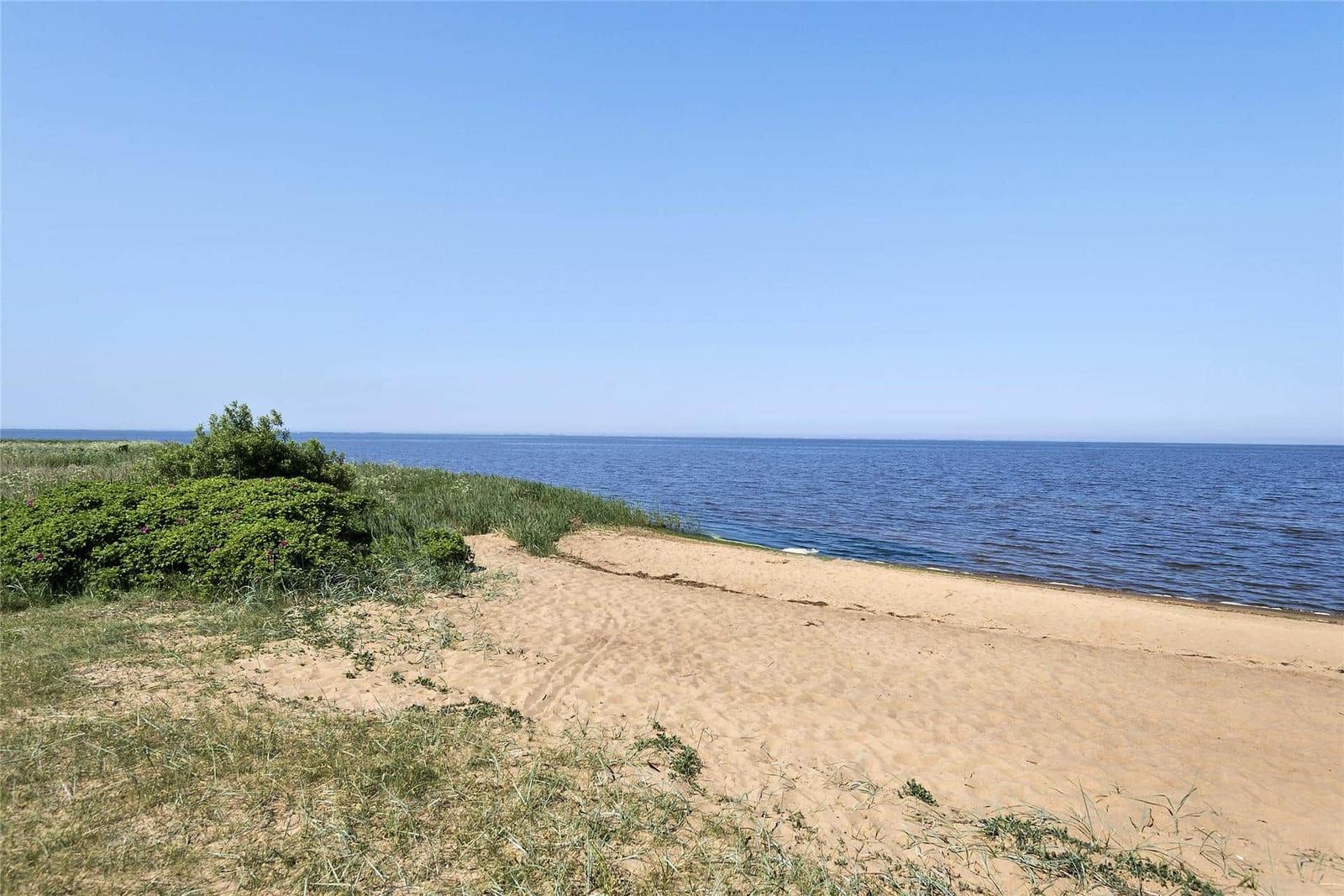 Grünes Gras am Strand mit Picknicktisch und Blick auf das Meer unter blauem Himmel.
