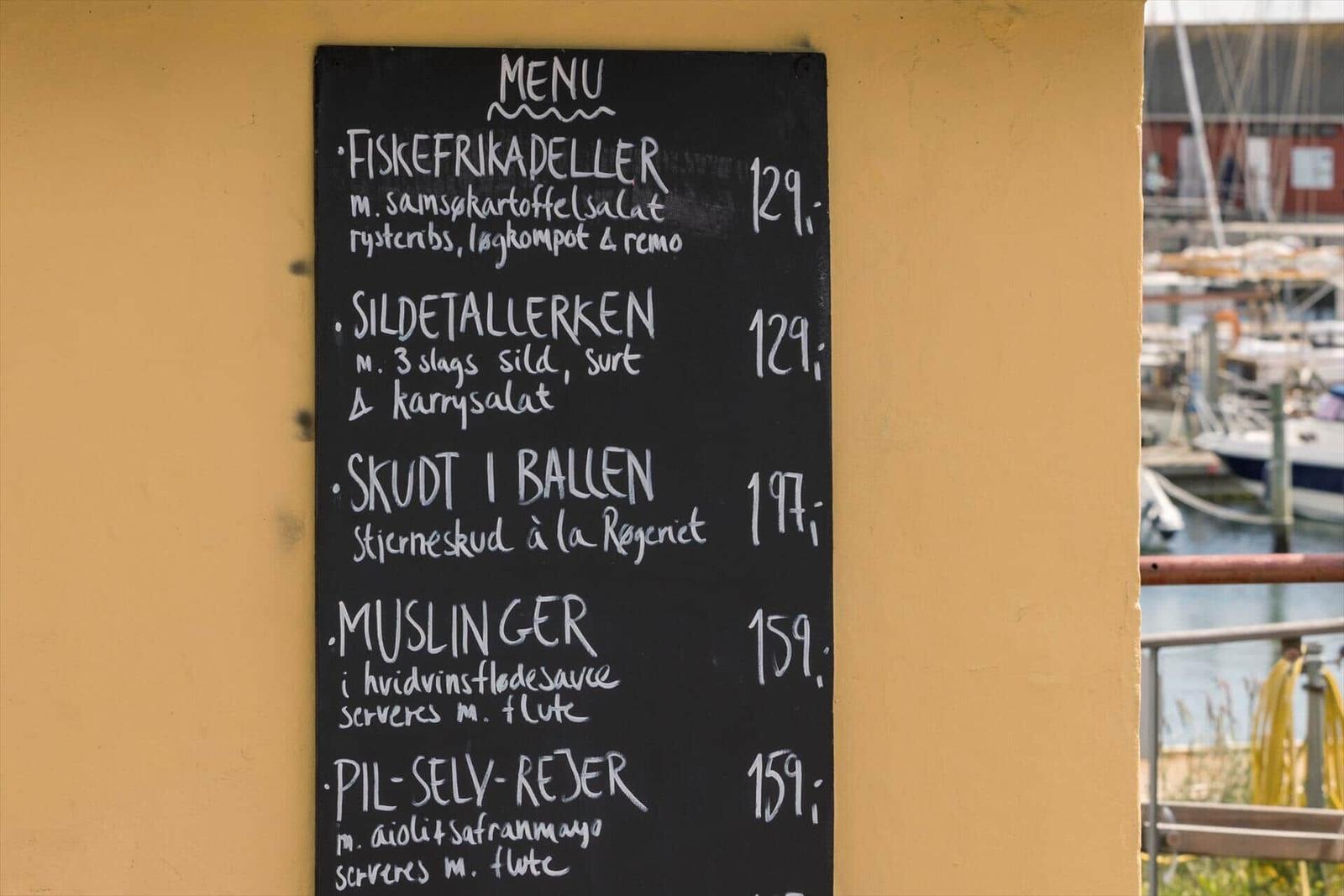 E-Bikes zum Mieten an einem Wasserufer mit Fahrradfahrern im Hintergrund.
