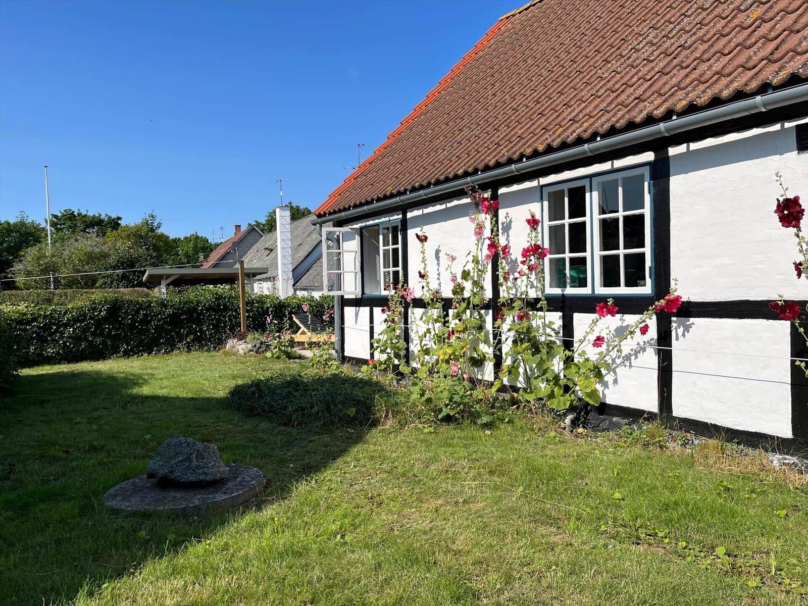 Ein Haus mit strohgedecktem Dach, roter Tür und Fenstern, daneben hängt eine dänische Flagge.