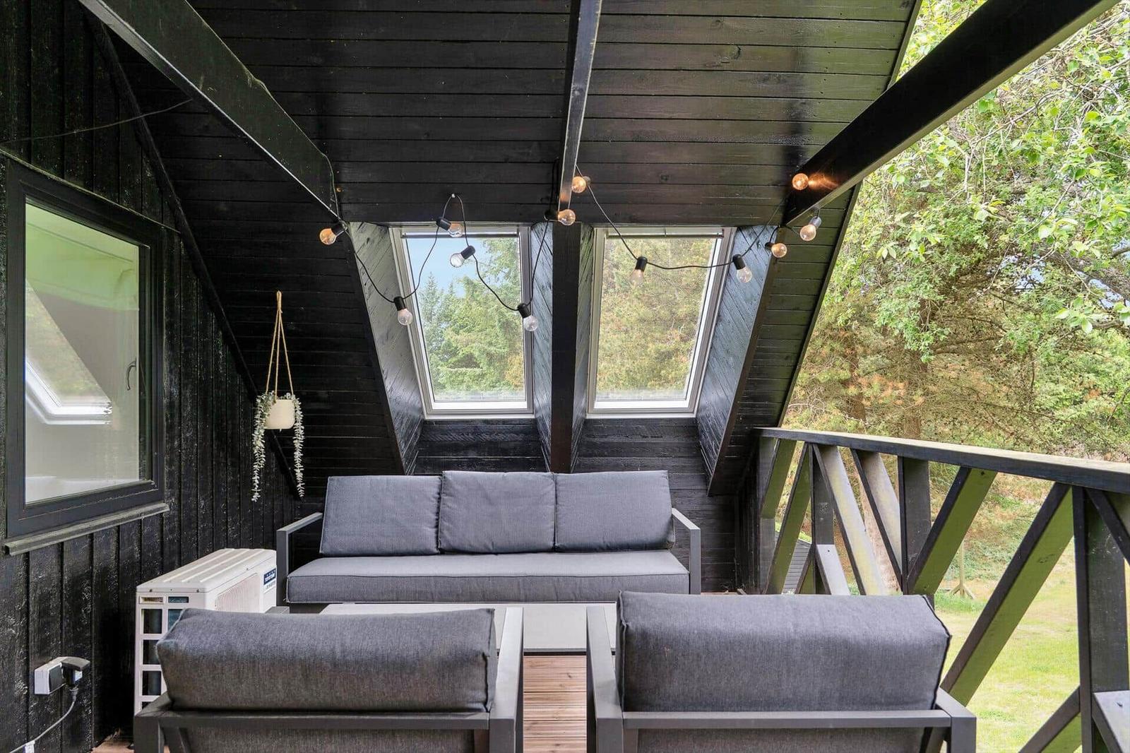 Holzsauna mit Sitzbänken und Kissen, Wanduhr und Informationsplakat.