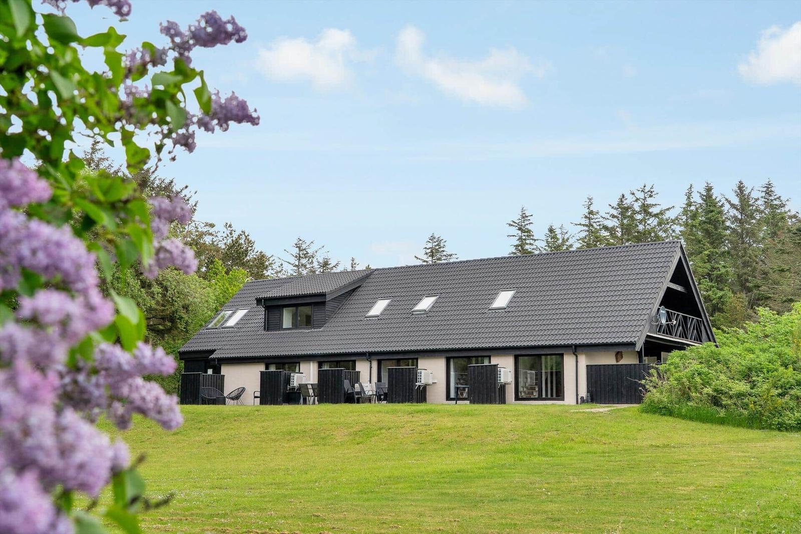 Schwarzes Holzhaus mit Balkon und Glasfront im Grünen