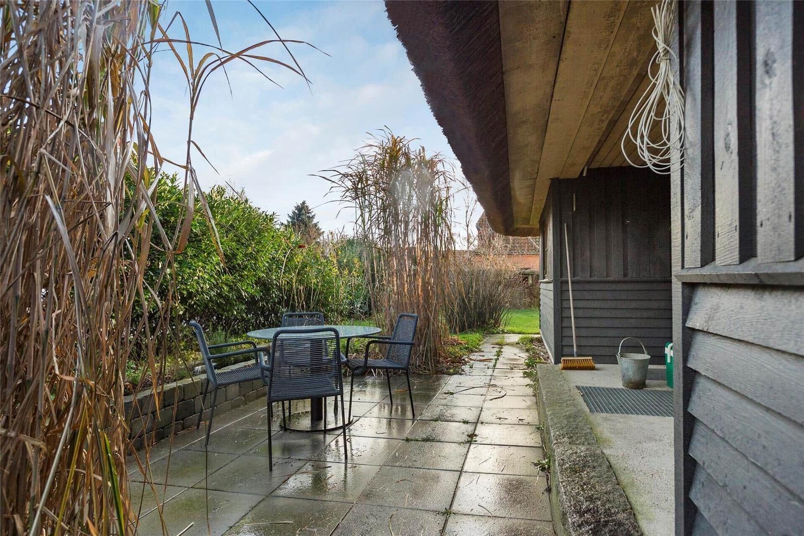 Zwei Stühle mit Decken stehen vor großen Fenstern mit Blick auf Garten.
