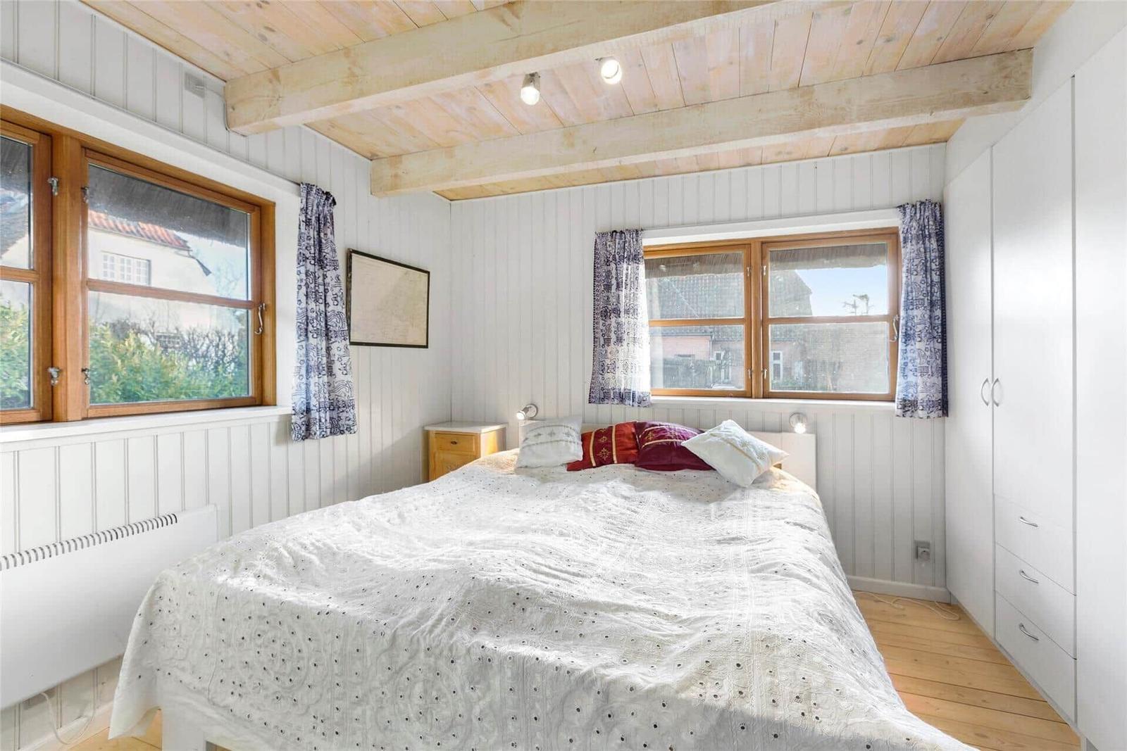 Badezimmer mit Toilette, Waschbecken und runden Spiegel an weißen vertikalen Paneelen.