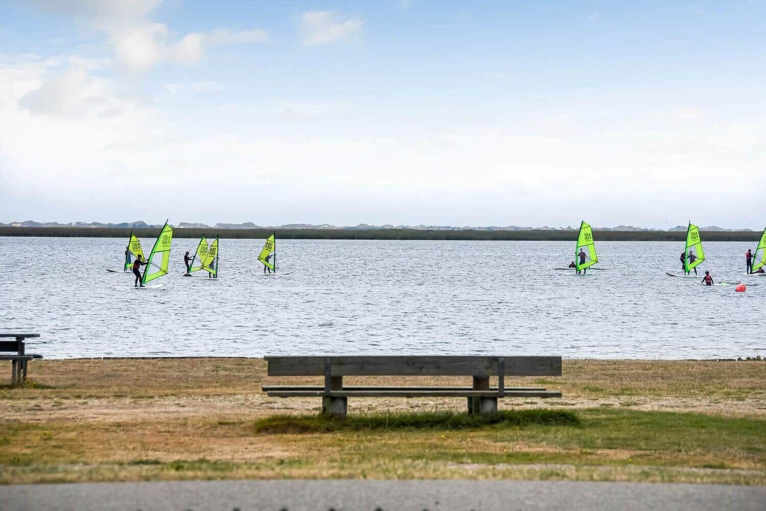 Rote Holzhäuser am Wasser mit blauem Boot und zwei Personen im Hintergrund.