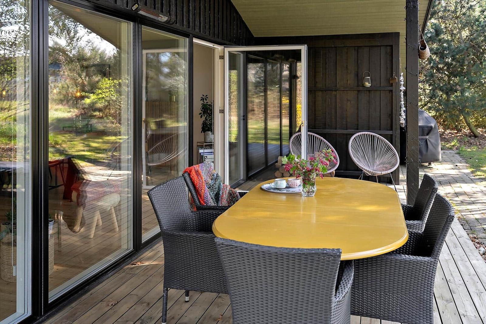 Terrasse mit Sitzgruppe unter Sonnensegel und Pflanze.