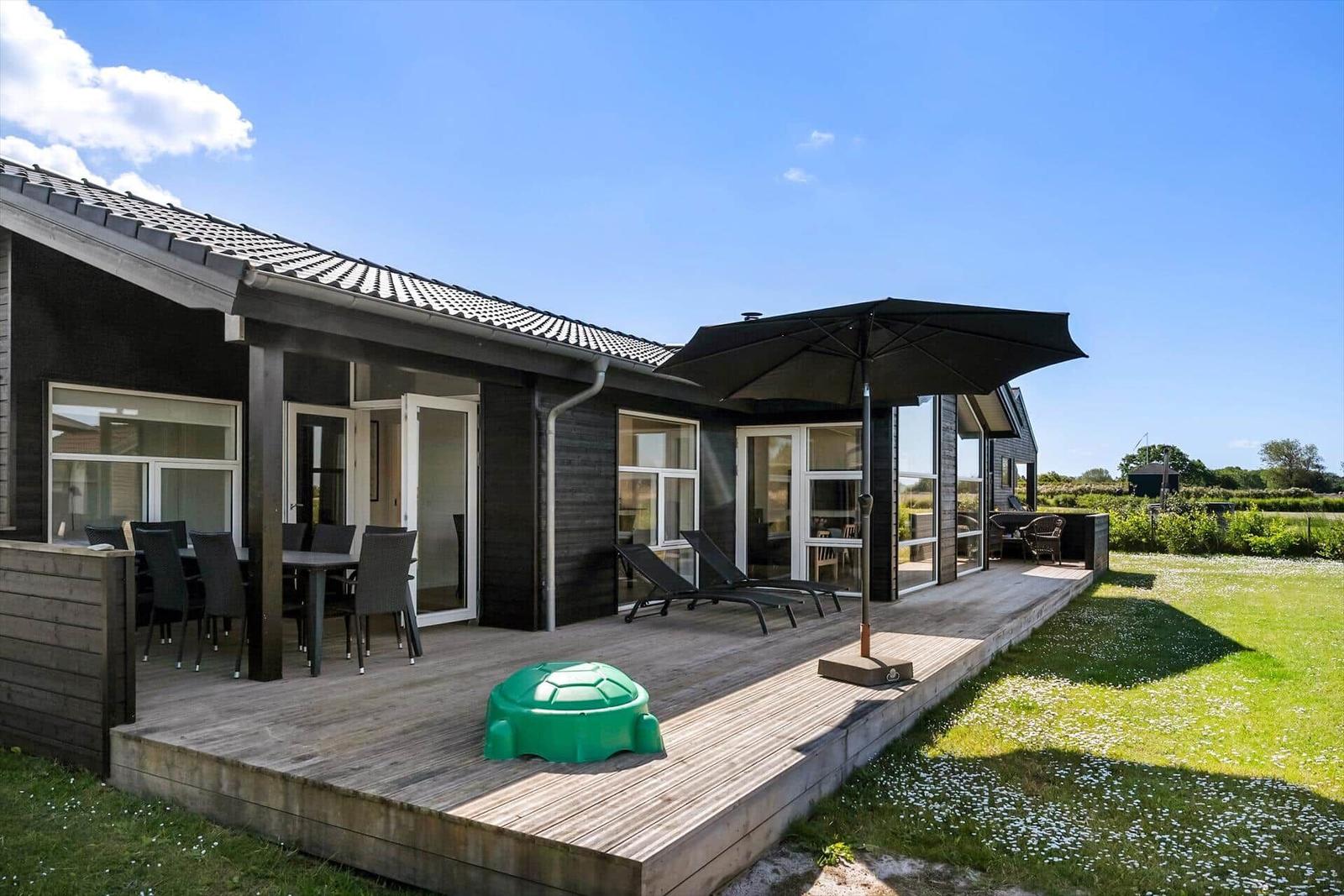 Moderne Villa mit Terrasse und Garten. Blick auf Felder und Himmel.
