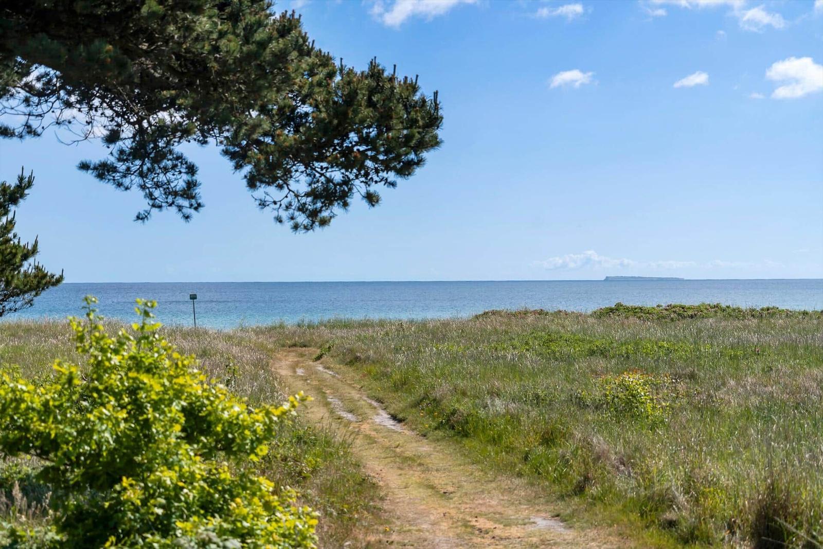 Hafen mit Booten, Strand und Dorf im Hintergrund.