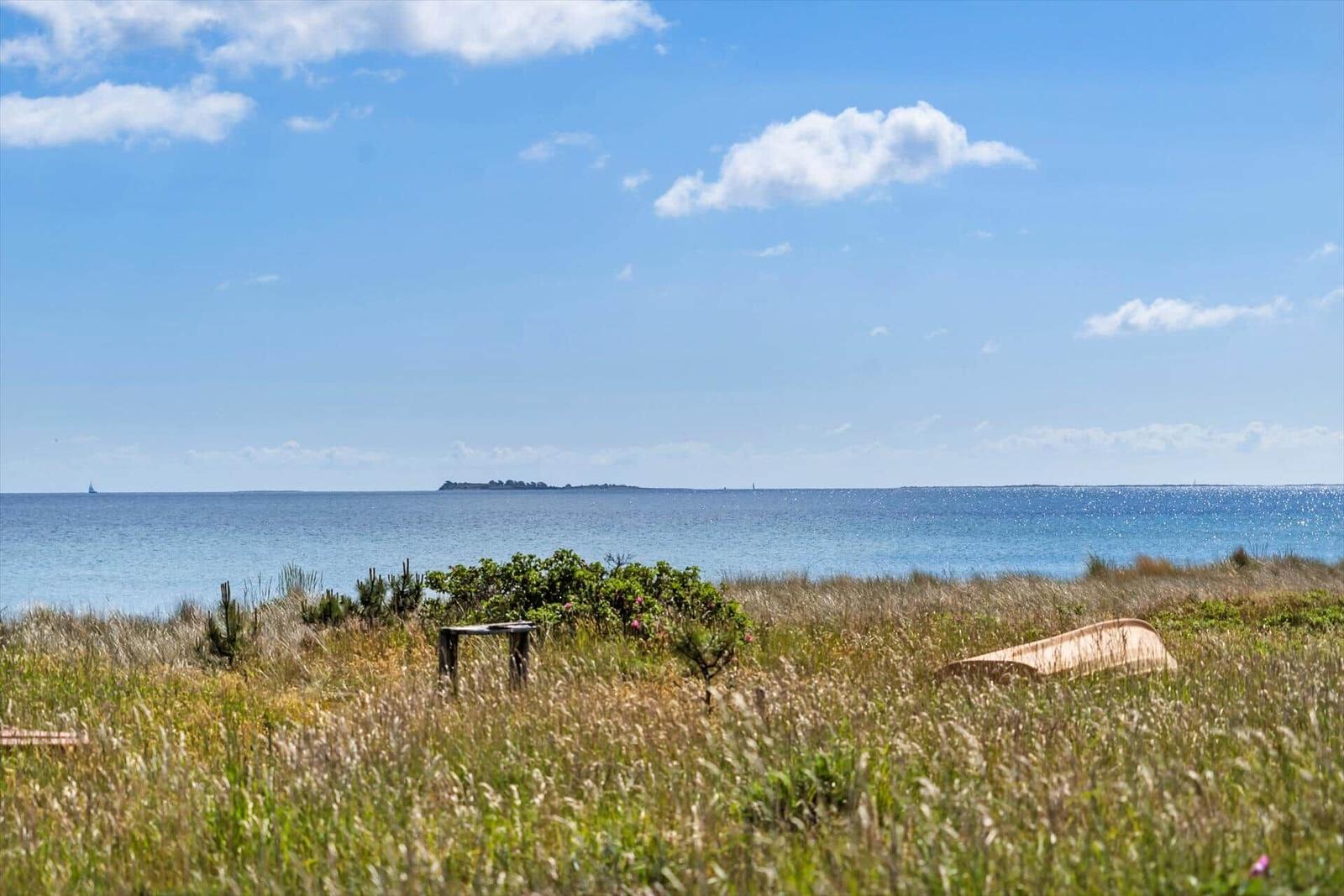 Aerial view of a coastal peninsula with sandy beach and green dunes.