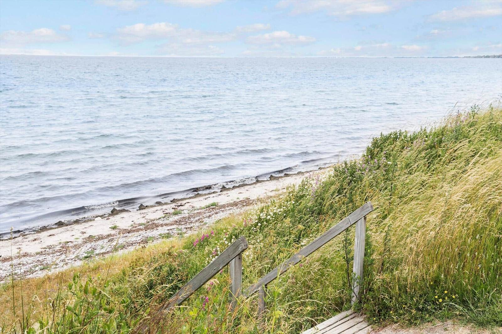 Grüner Rasenbereich mit Bänken und Tischen am Meer.