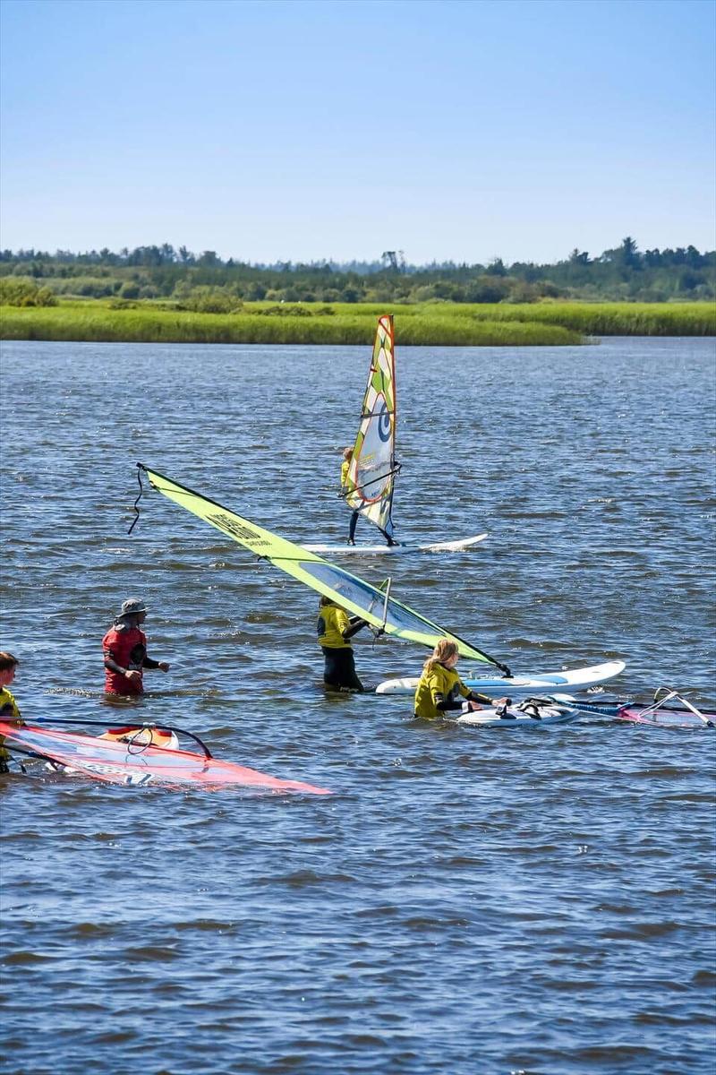 Windsurfers prepare in the water for sailing.