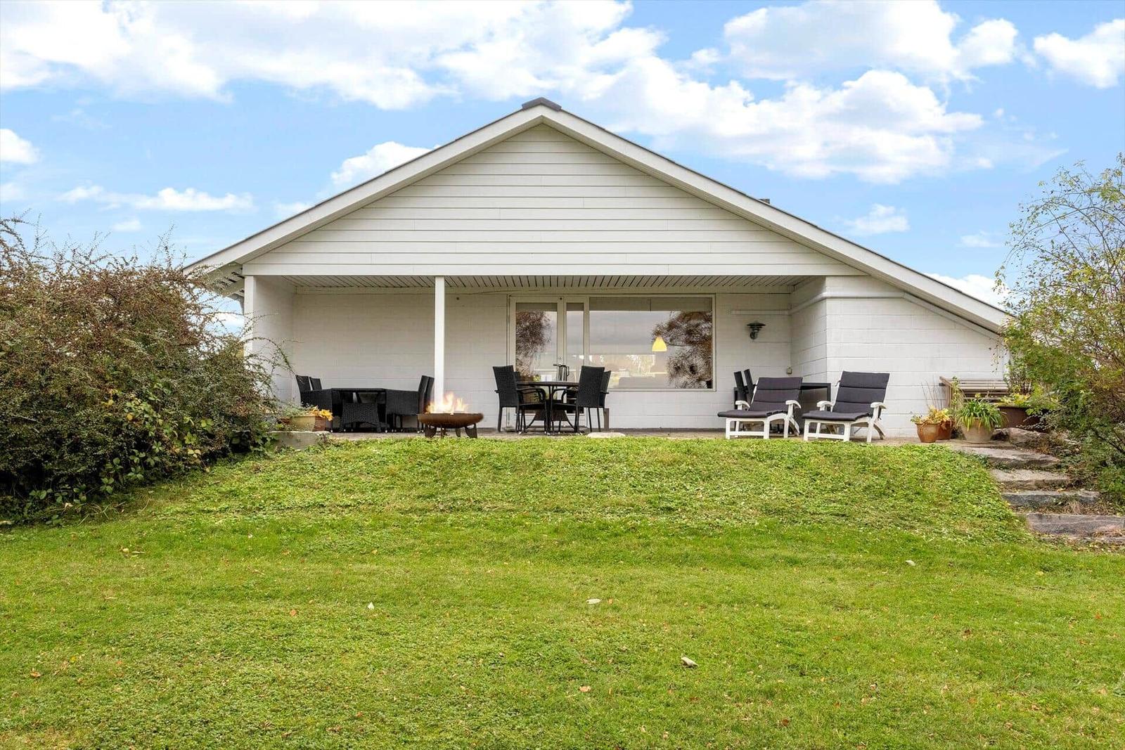 Large green lawn area with trees and shrubs in the background.