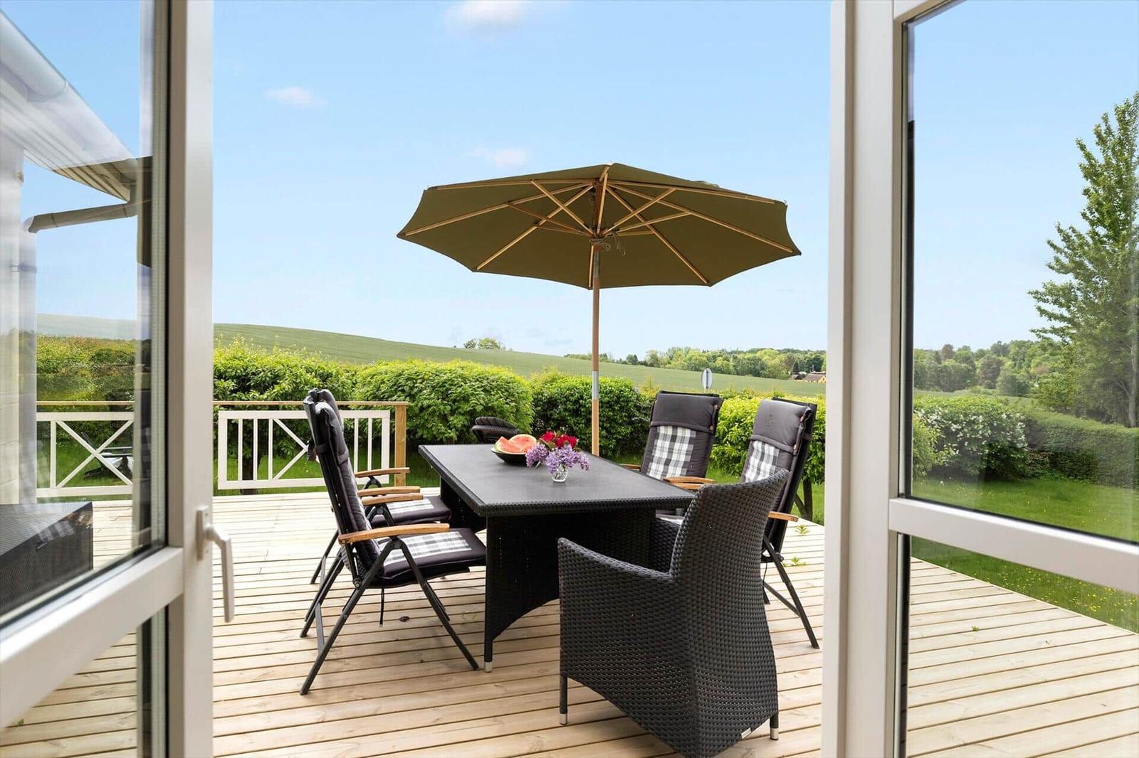 Table with watermelon and flowers in front of open door to living area.