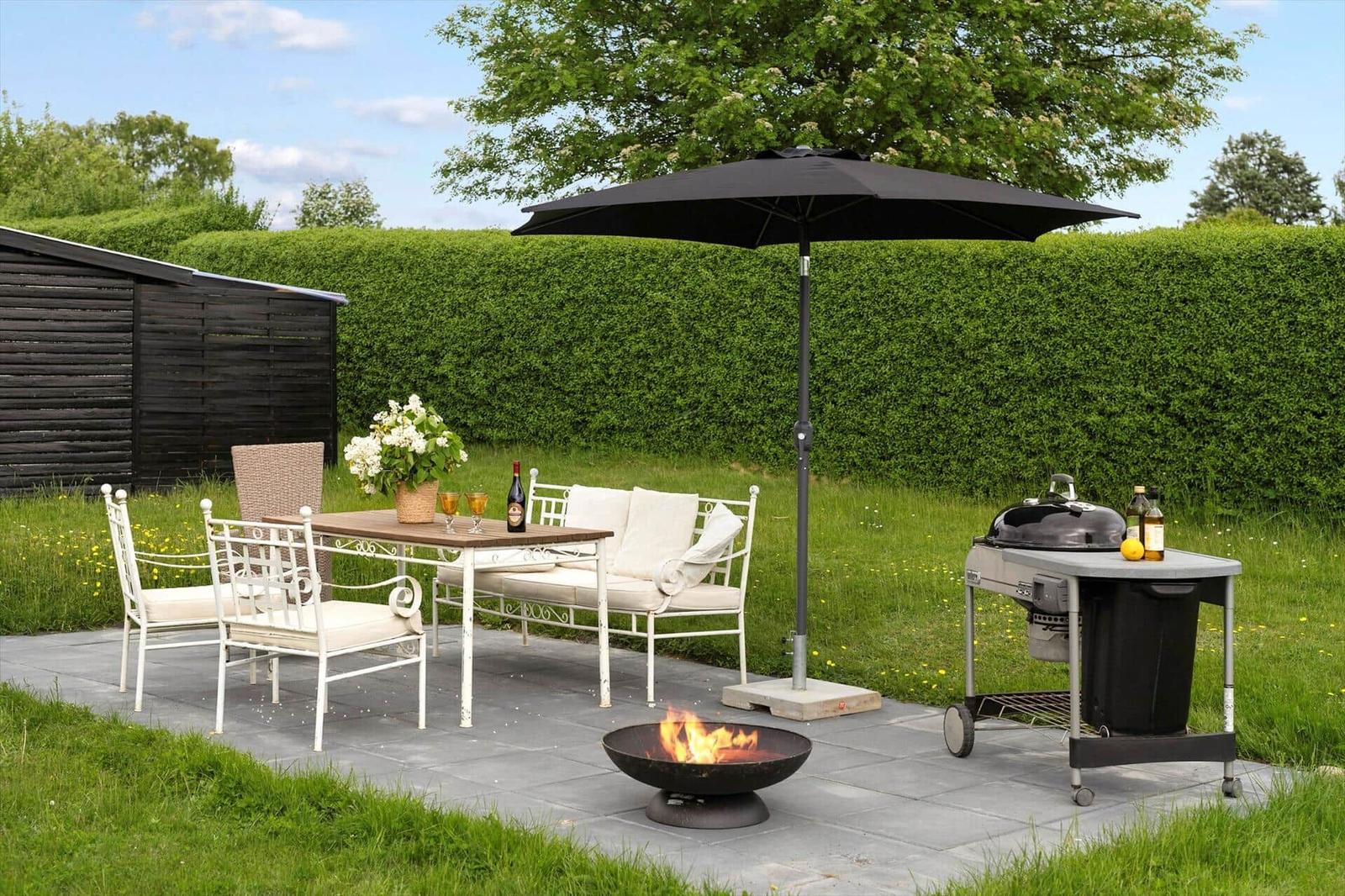 A black lounge chair with a white blanket in the green garden.