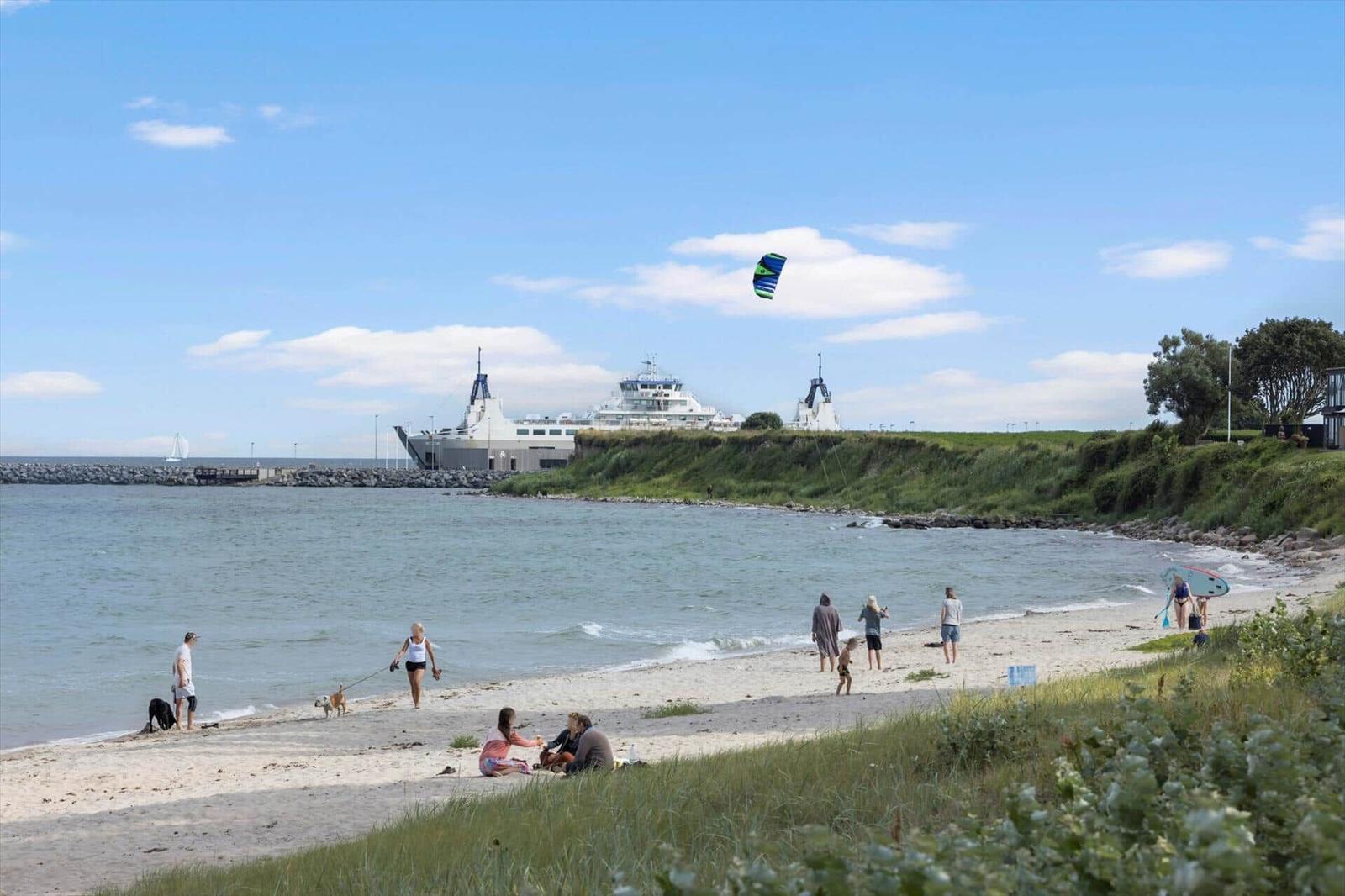 Hafen mit Booten, Strand und kleinem Dorf in ländlicher Umgebung.