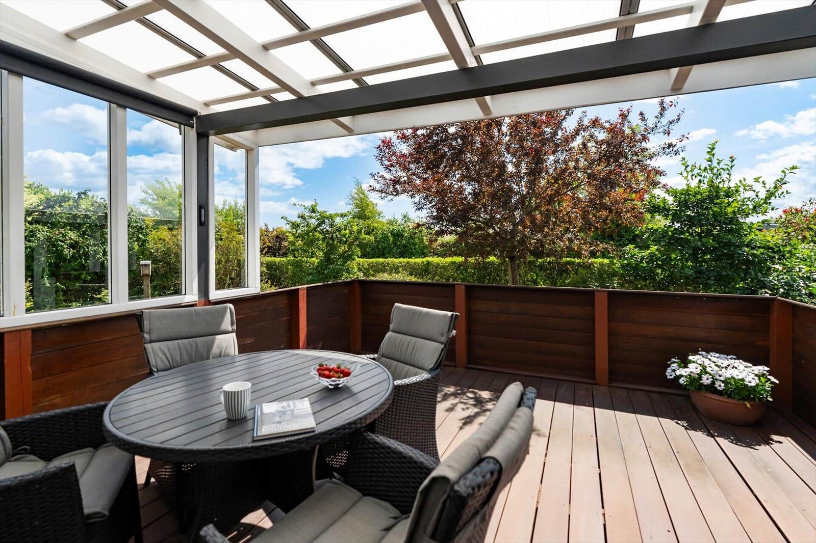 Terrace with table, chairs, and view of playground and garden.