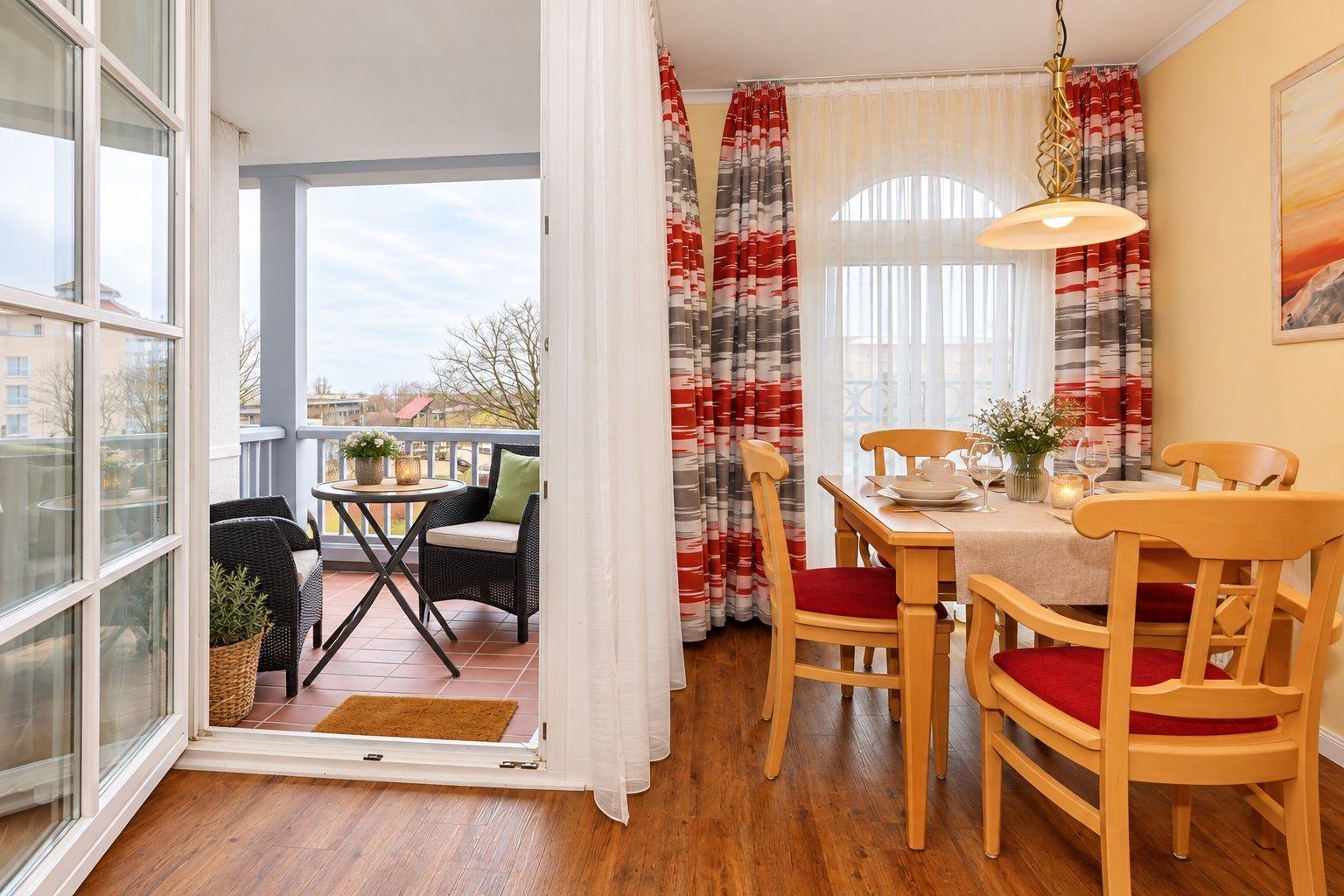 Esszimmer mit Holztisch, Stühlen und Blick auf Balkon mit Tisch und Stühlen.