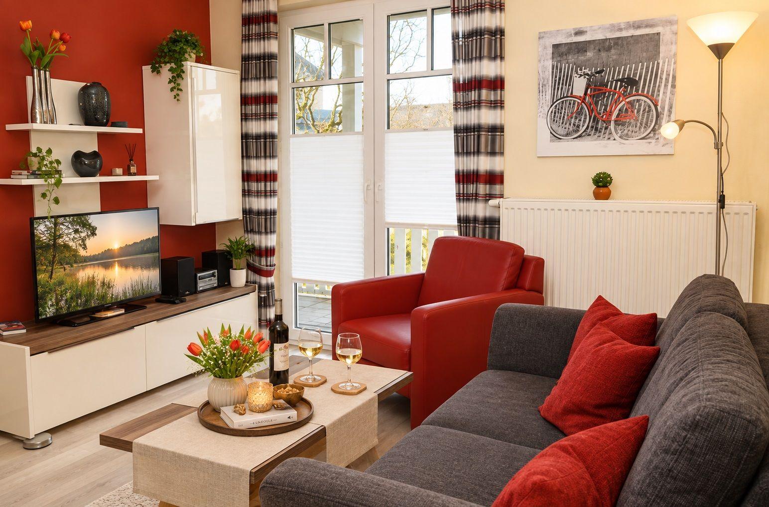 Wohnzimmer mit Sofa, Sessel, Fernseher und Tisch.