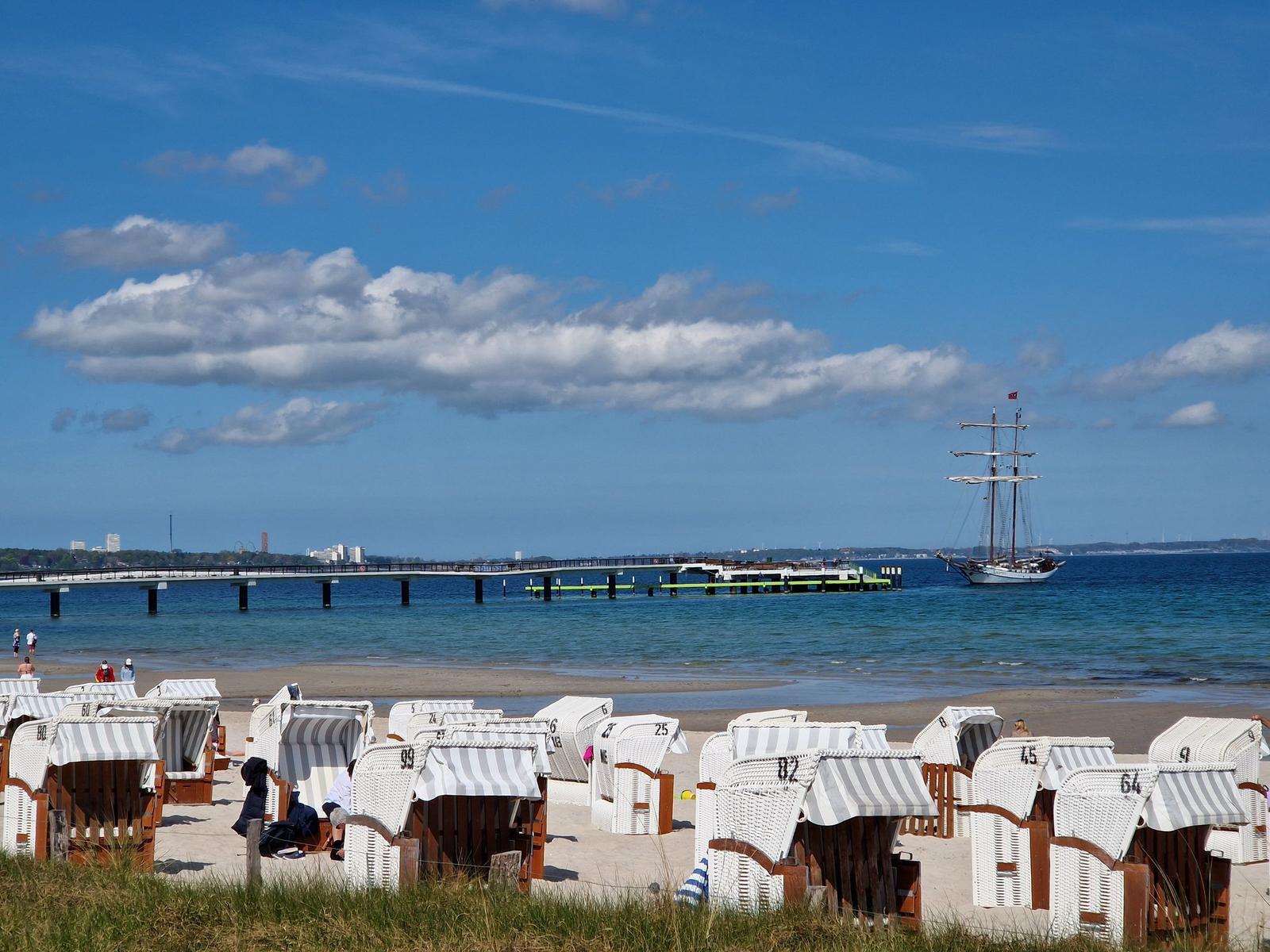 Strand mit Liegestühlen und Schiffen im Hintergrund.