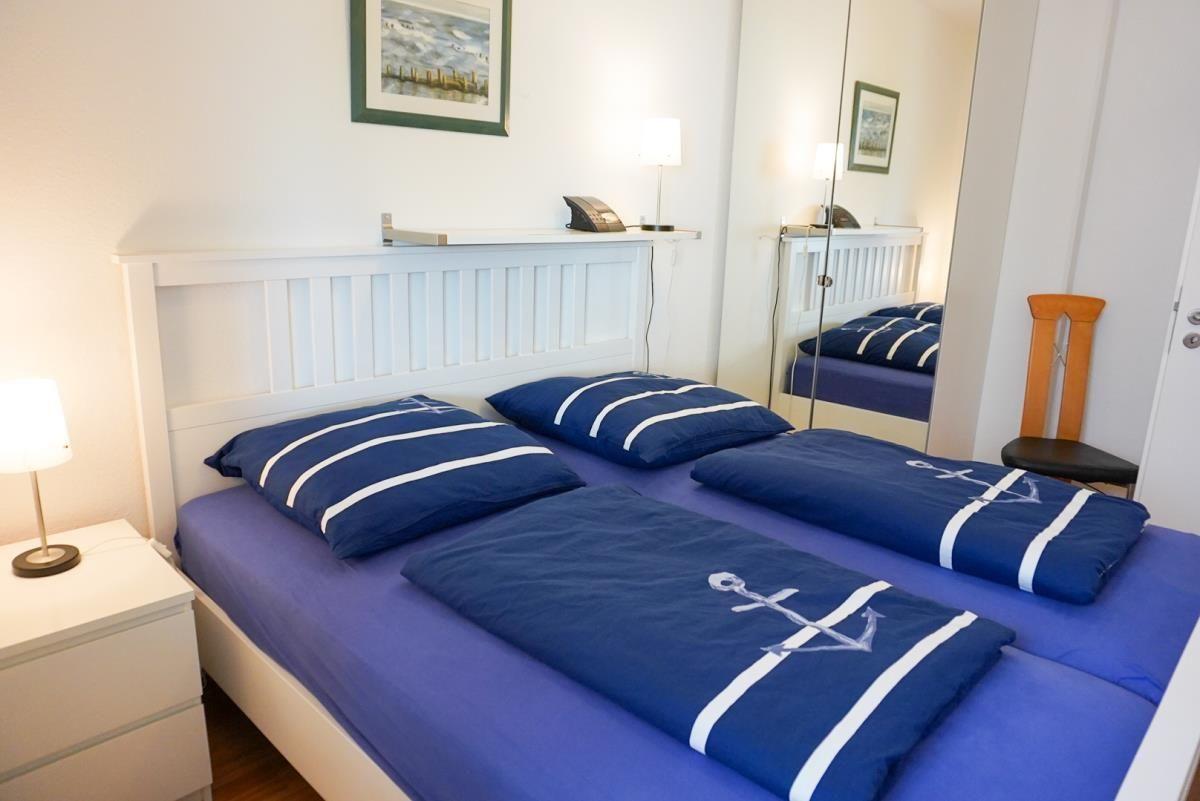 Gemütliches Schlafzimmer mit maritimer Bettwäsche und modernen Annehmlichkeiten.