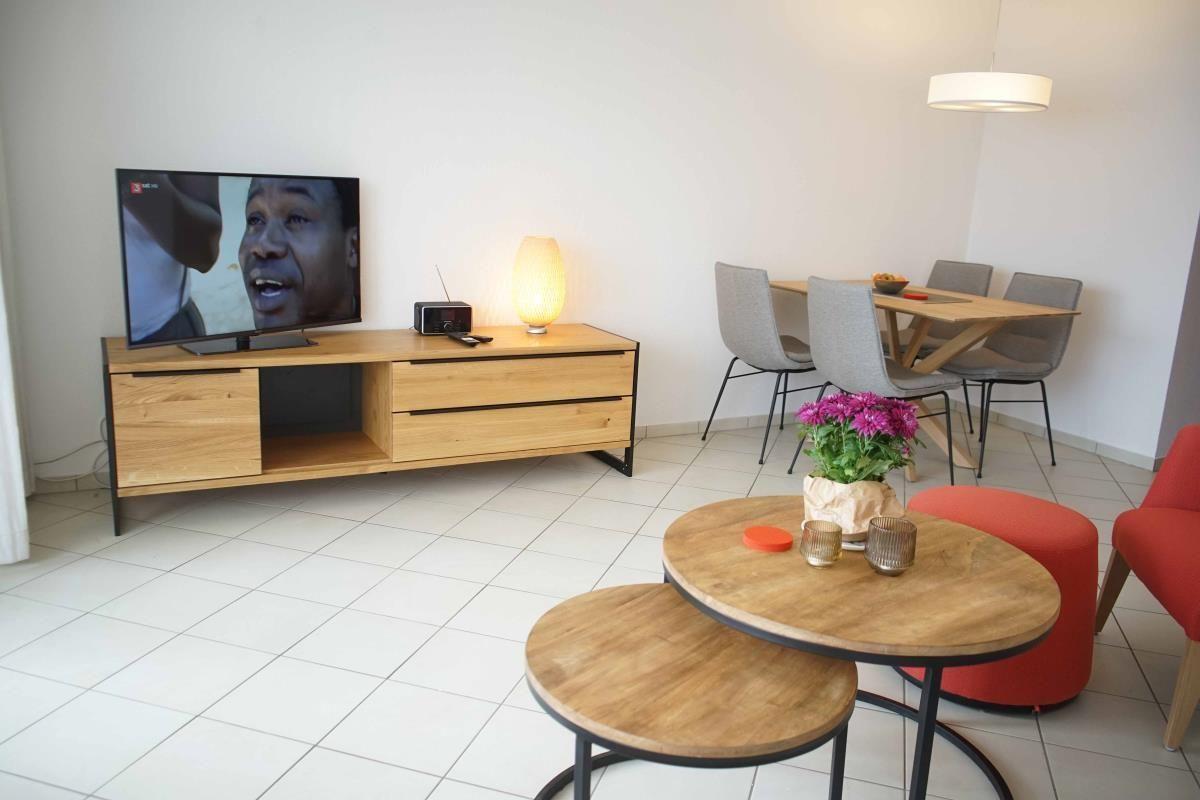 Gemütliches Wohnzimmer mit Fernseher und Esstisch