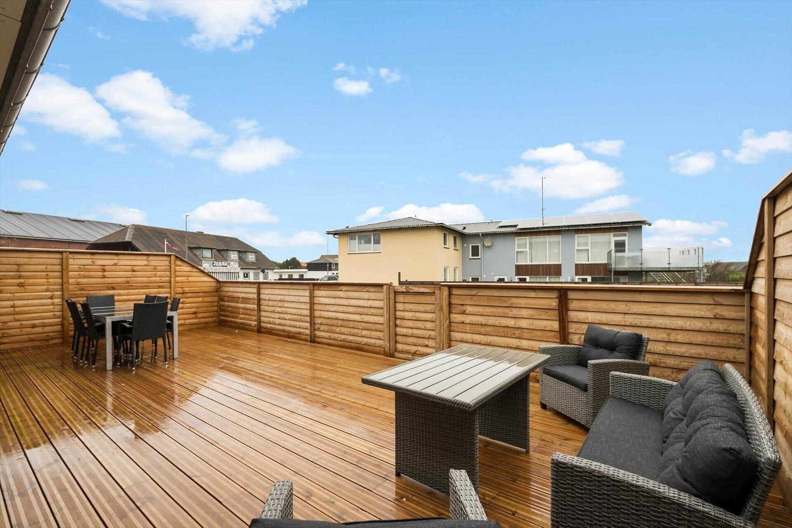 Terrasse mit Tisch und Stühlen, Holzgeländer und Blick auf Nachbarhaus.