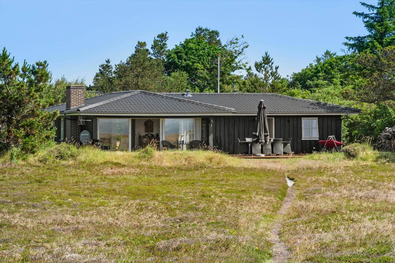 Moderne Ferienwohnung mit Terrasse und Garten. Holzwand und Glasfront sichtbar.