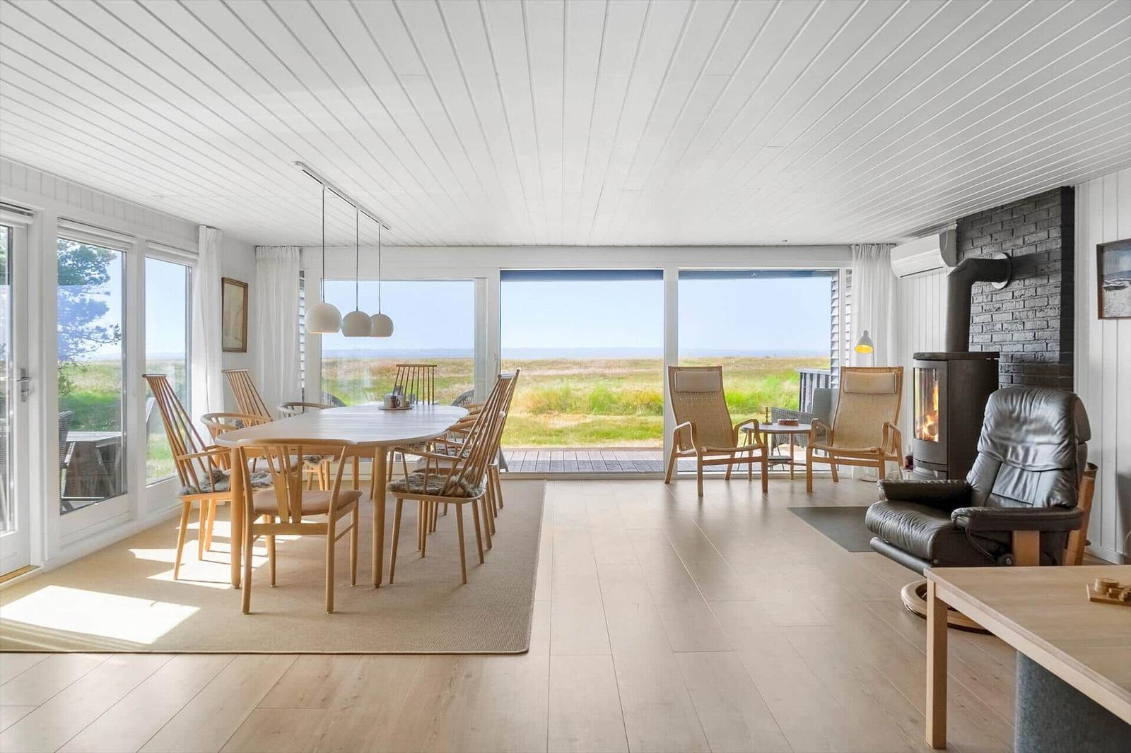 Terrasse mit Sitzgruppe und Blick auf Grasland und Meer.