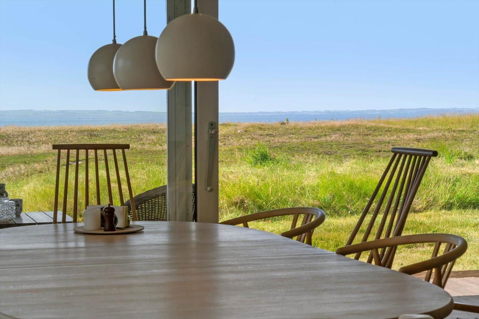 Ein steiniger Pfad führt durch grünes Grasland direkt zum Horizont und Meer.