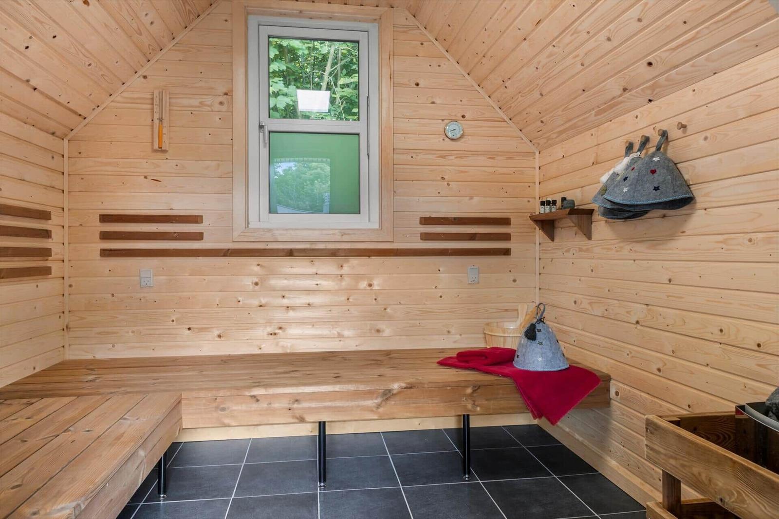 Schwarze Sauna mit Schild BEDSTES HYTE in grünem Garten
