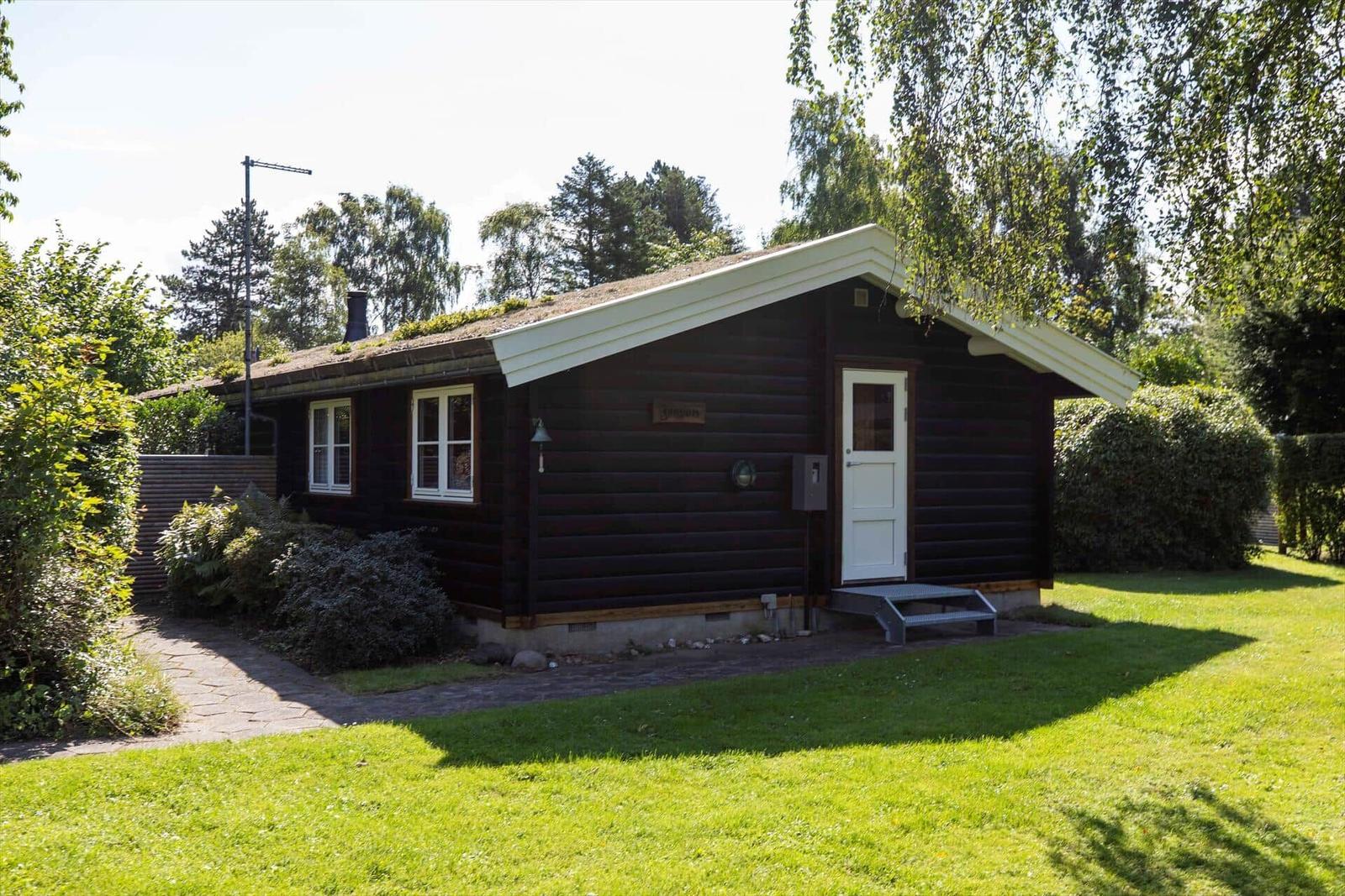 Küche und Essbereich mit Holzwand und -decke, weißer Tisch, roter Teppich und Fenster.