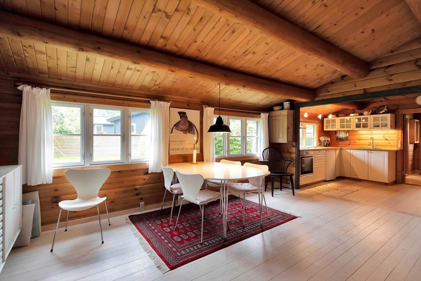 Schlafzimmer mit Holzwand, Fenster, Bett und Küchenzeile.