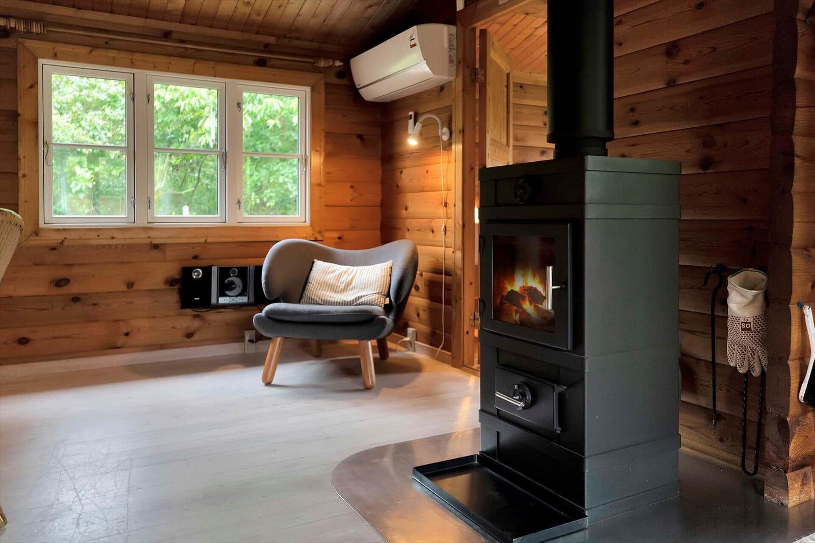 Esszimmer mit Holztisch, Stühlen und Wandbild. Holzwände und Fenster mit Blick nach draußen.