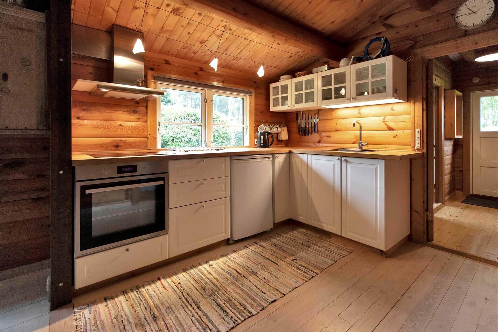 Holzhaus mit weißen Fenstern und Tür, umgeben von Grünfläche und Bäumen.