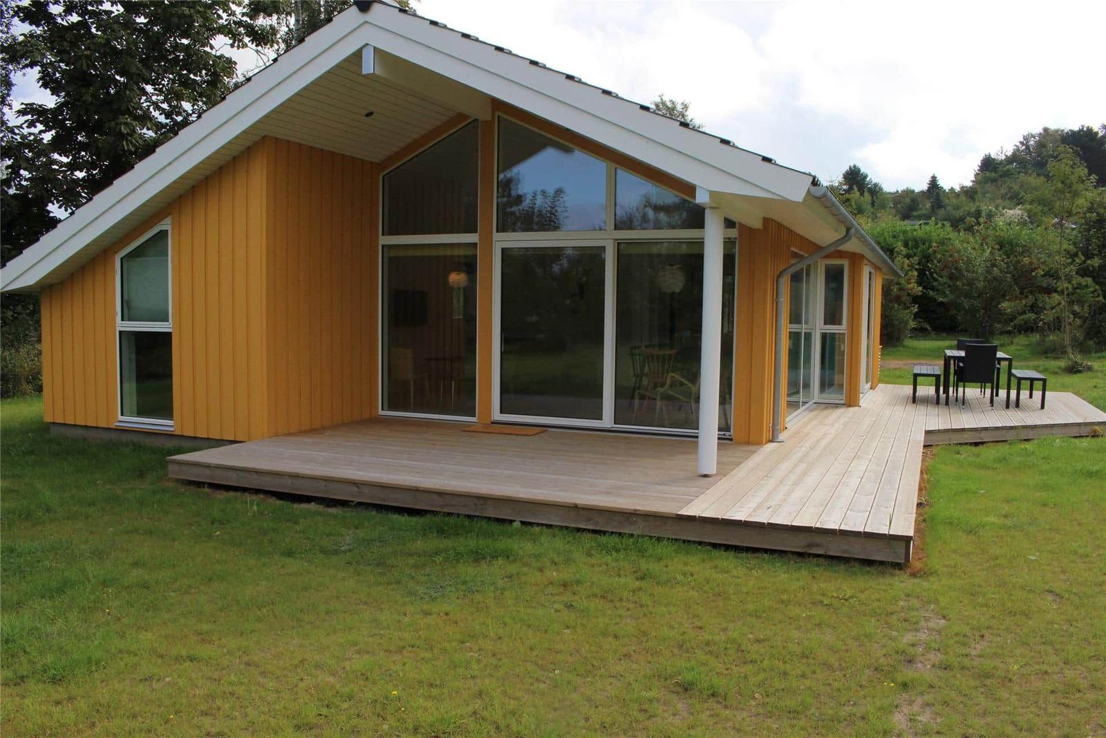 Schlafzimmer mit Bett, Stuhl und Hochstuhl. Holzwände und Fensterblick auf Gras.