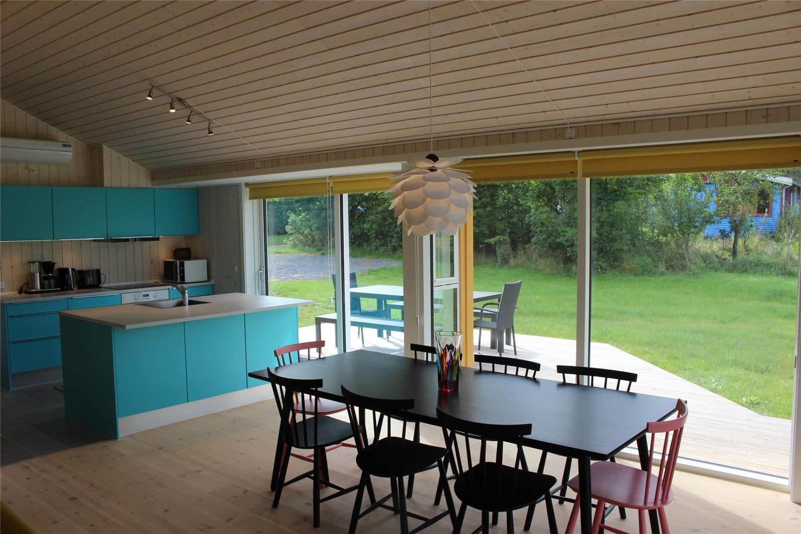 Moderne Holzhütte mit Terrasse, Glasfront und Garten. Außentisch mit Stühlen.