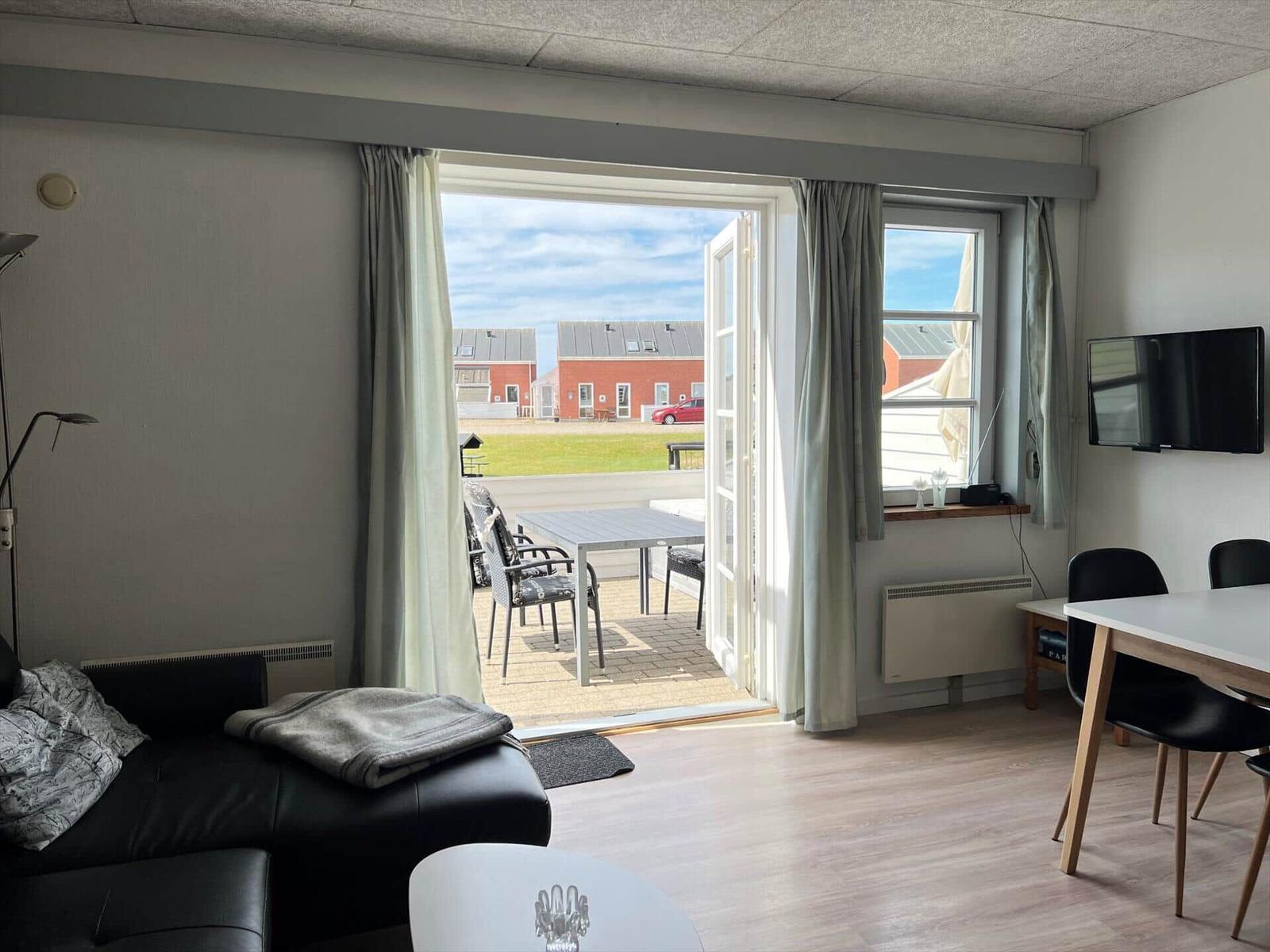 Reihen von roten Backsteinhäusern mit weißen Fensterrahmen und Dächern. Grasfläche mit Spielplatz im Vordergrund.