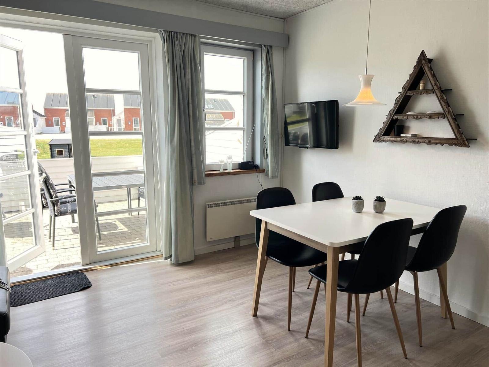 Terrasse mit Tisch, Stühlen und Grill. Holzterrasse und Sitzgelegenheiten im Hintergrund.