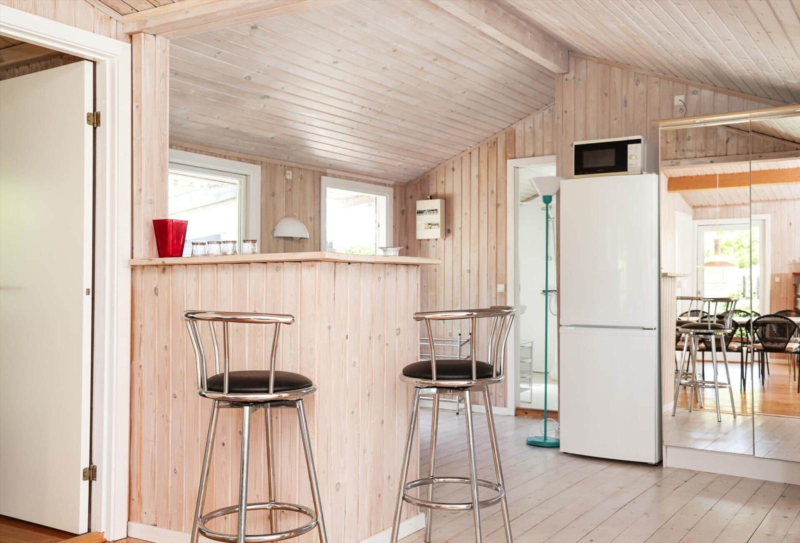 Kitchen with wooden walls and ceiling, white cabinets, and stainless steel stove.