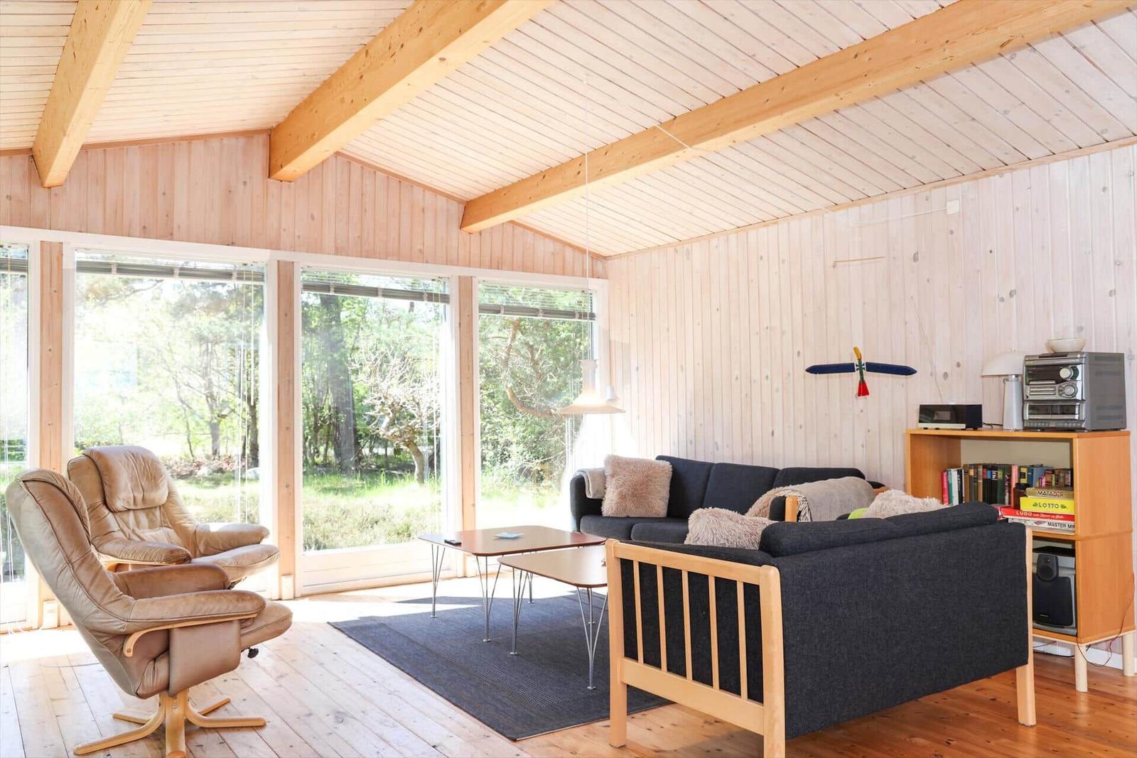 Bedroom with wooden walls, window with blinds, and bed with white pillows.