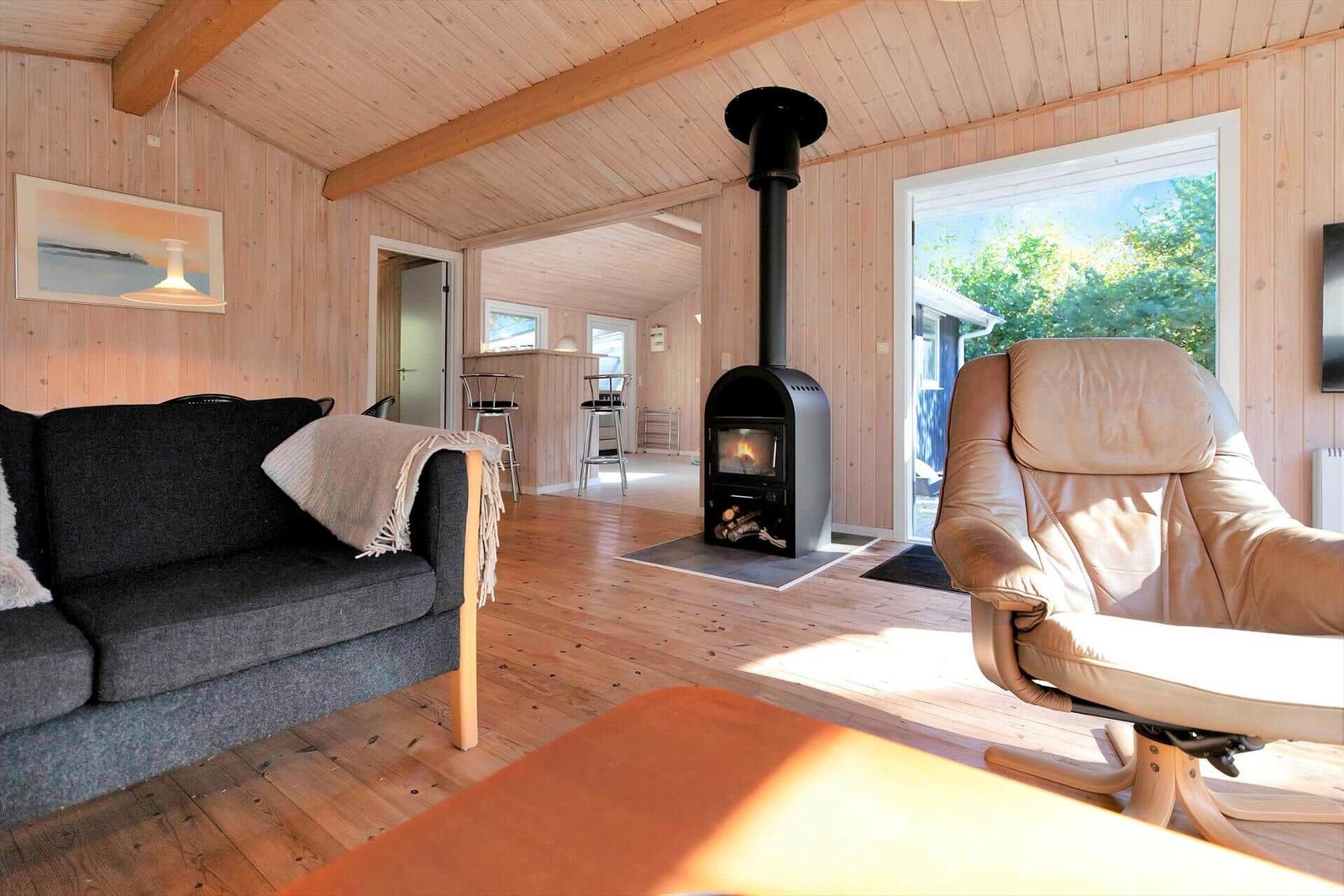 Room with bed and baby crib with Winnie the Pooh motif, wooden walls and window with blinds.